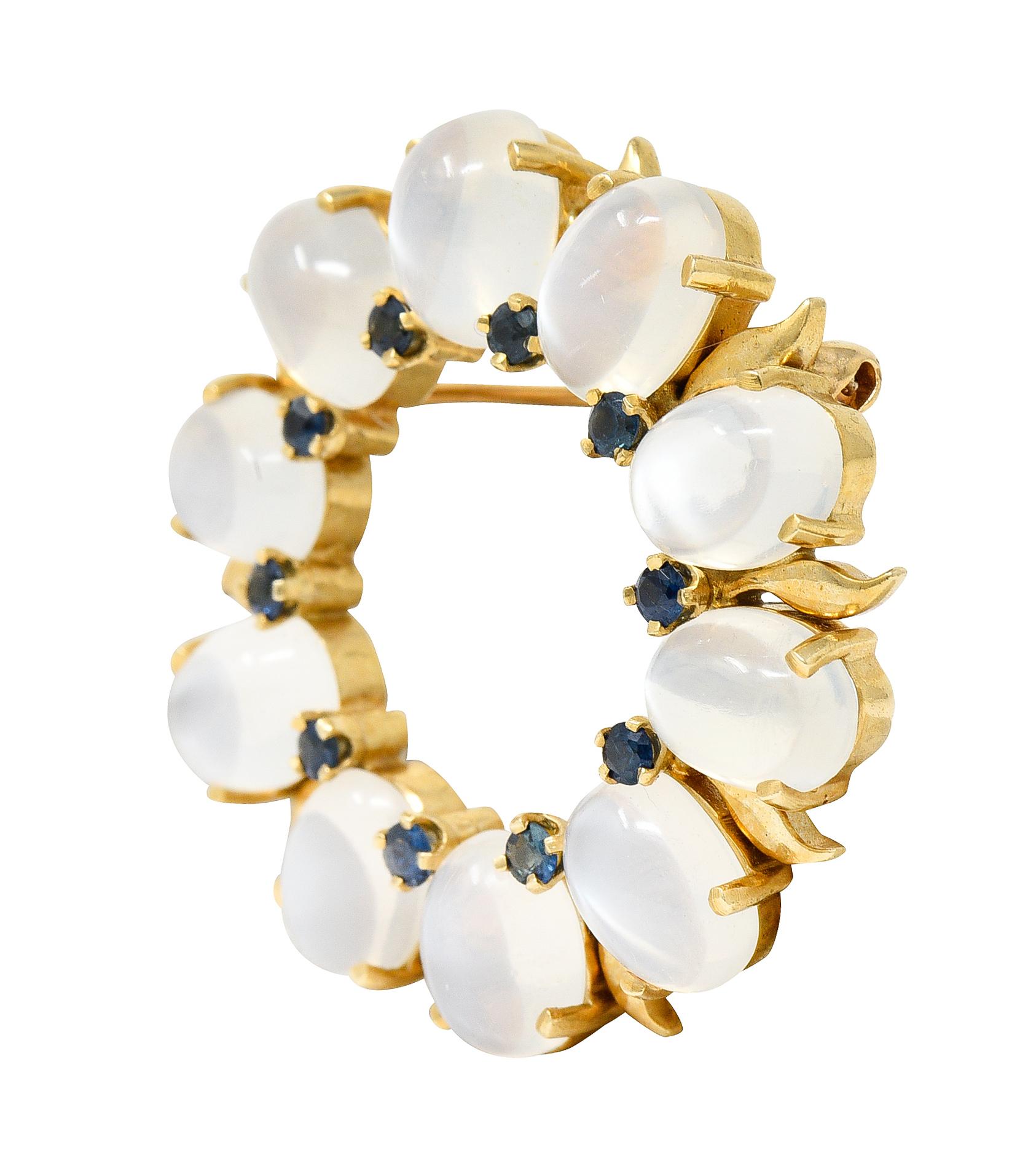 Circular brooch is a radial pattern with prong set gemstones and high polished gold leaf motif

Featuring 6.0 x 8.0 mm oval cabochon moonstones - translucent with billowing white adularescence

Alternating with round cut sapphires - weighing