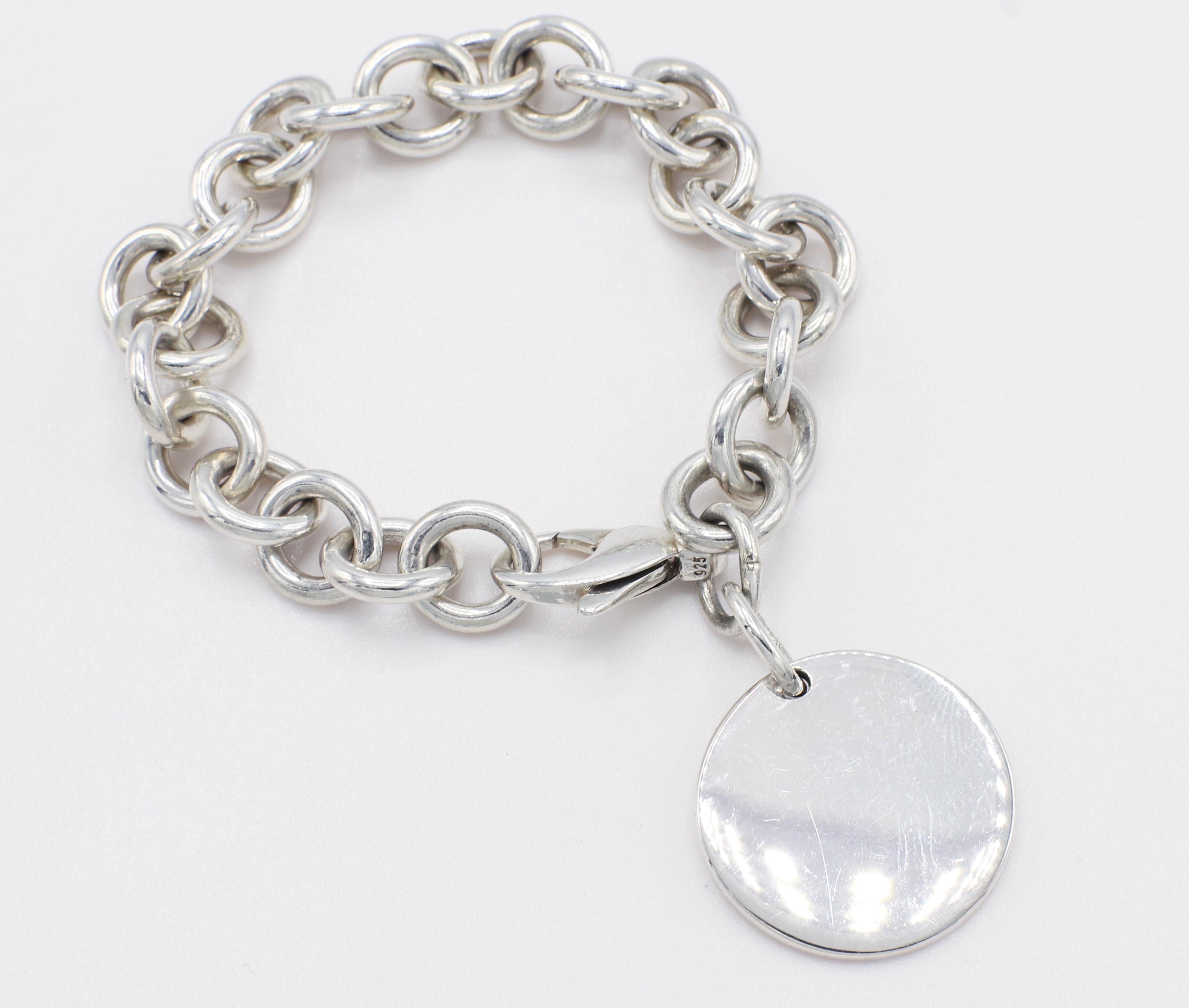 Tiffany & Co. Return to Tiffany Sterling Silver Disc Charm Link Bracelet 
Metal: Sterling silver 925
Weight: 35.49 grams
Length: 6.75 inches
Pendant diameter: 23.5 MM
Signed: Please Return to Tiffany & Co. New York 925

