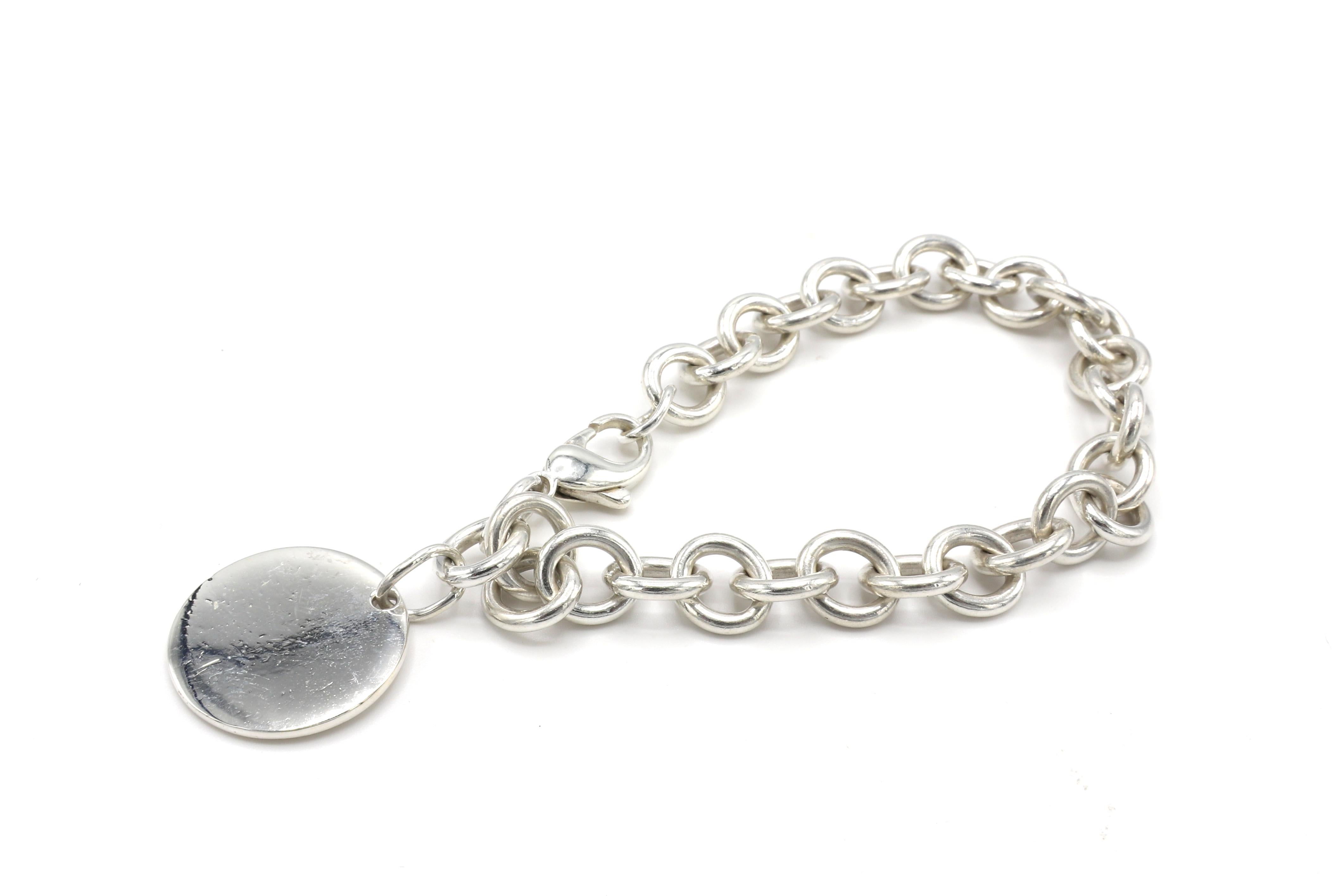Tiffany & Co. Return to Tiffany Sterling Silver Disc Charm Link Bracelet 
Metal: Sterling silver 925
Weight: 38.6 grams
Length: 8.5 inches
Pendant diameter: 23.5 MM
Signed: Please Return to Tiffany & Co. New York 925
Condition: Slight scratches to