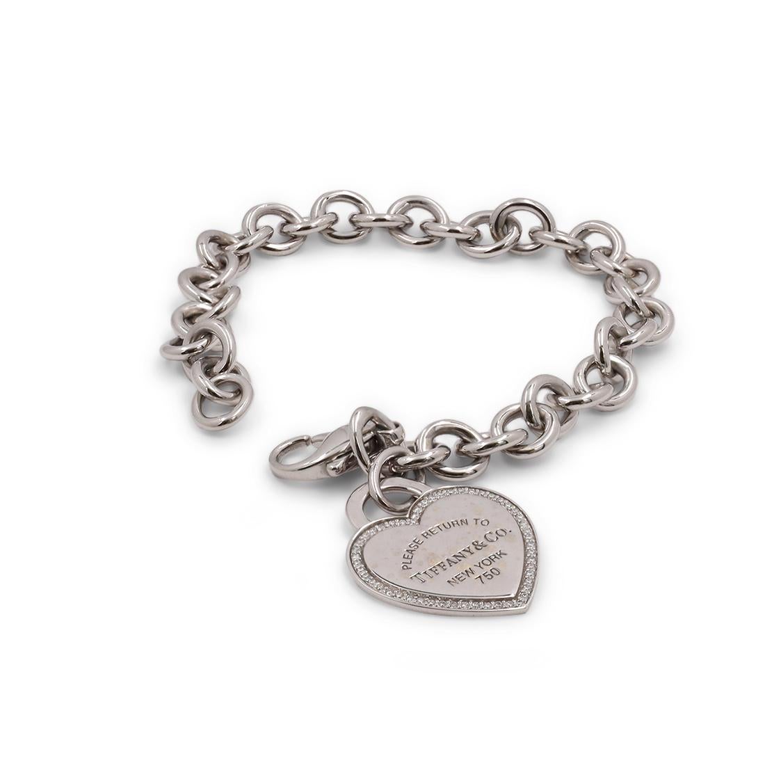 Authentic Tiffany & Co. 'Return to Tiffany' heart bracelet crafted in 18 karat white gold featuring the signature Tiffany & Co. engraving surrounded by an estimated 0.20 carats of round brilliant cut diamonds. The pendant measures 20.9mm in width x
