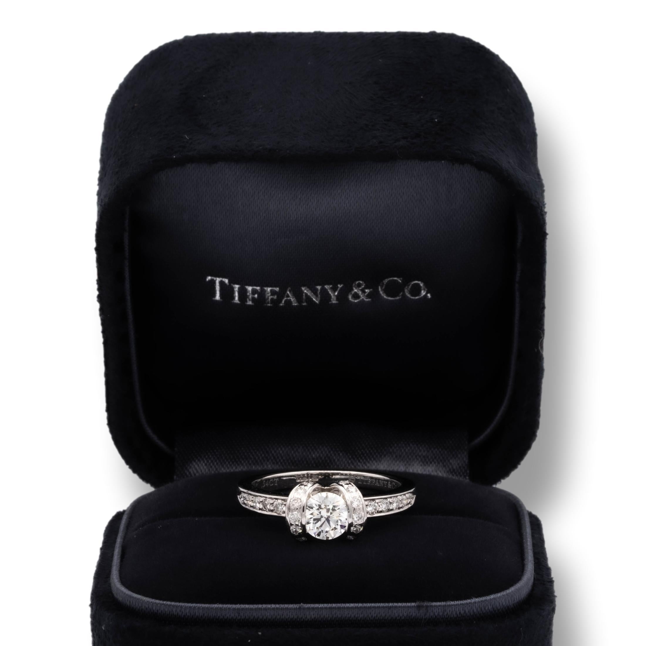 Tiffany & Co. Ribbon engagement ring finely crafted in platinum with a 0.54 ct round brilliant cut center diamond F color VVS1 clarity. The ring has channel set diamonds on each side weighing 0.36 carats total weight approximately.
The ring has been