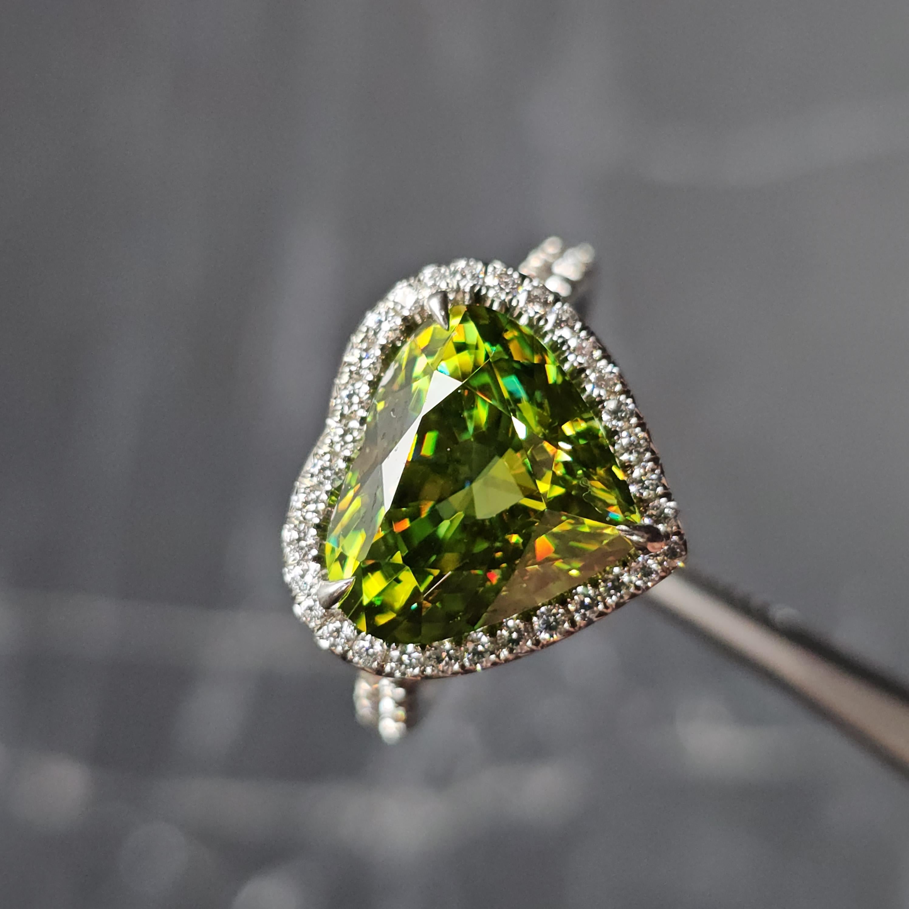 This gorgeous Tiffany & Co. ring is a stunning addition to any jewelry collection. Crafted from high-quality platinum and featuring a beautiful heart-shaped sphene/titanite stone, this ring is sure to turn heads. The ring is accented by a halo of