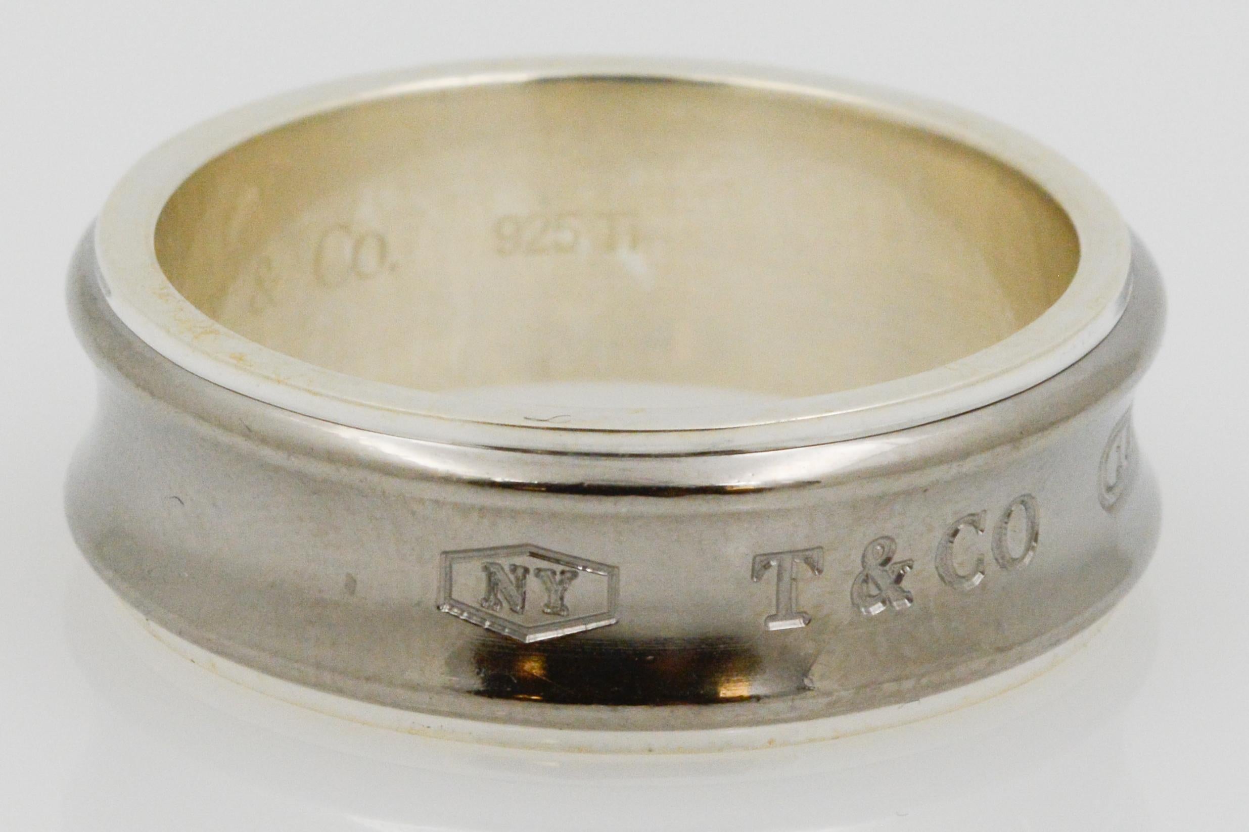 This Tiffany & Co. sterling silver ring has the T&CO logo with NY and 1887 stamped onto the front of the ring. The band has a concave middle that is unique to other silver rings. 
