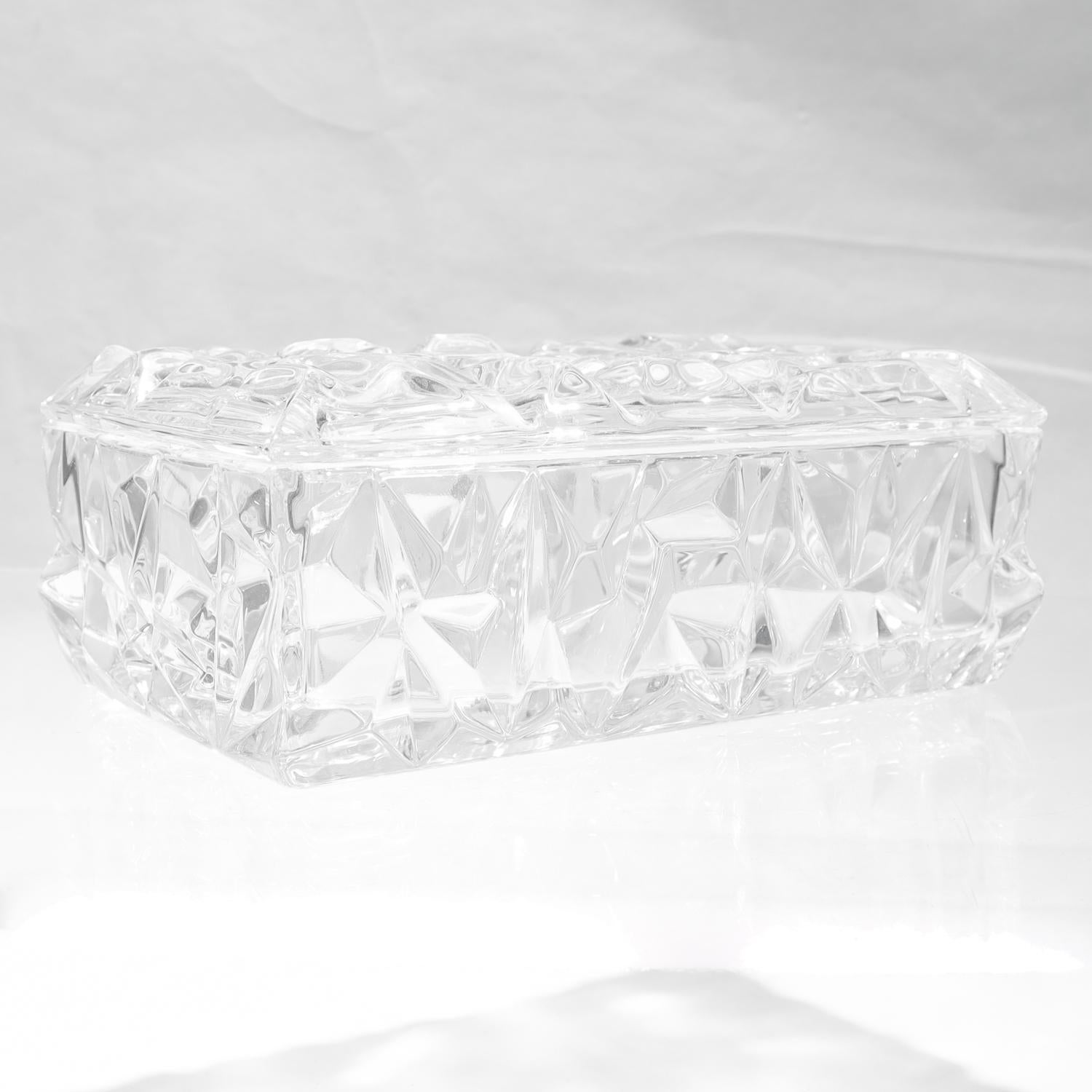 Un tocador o caja de baratijas de cristal fino.

De Tiffany & Co.

En el patrón Corte de roca.

Incluye caja y tapa. Todos los lados, excepto la base de la caja, están recubiertos de numerosos cortes en ángulo que crean un dibujo que recuerda al