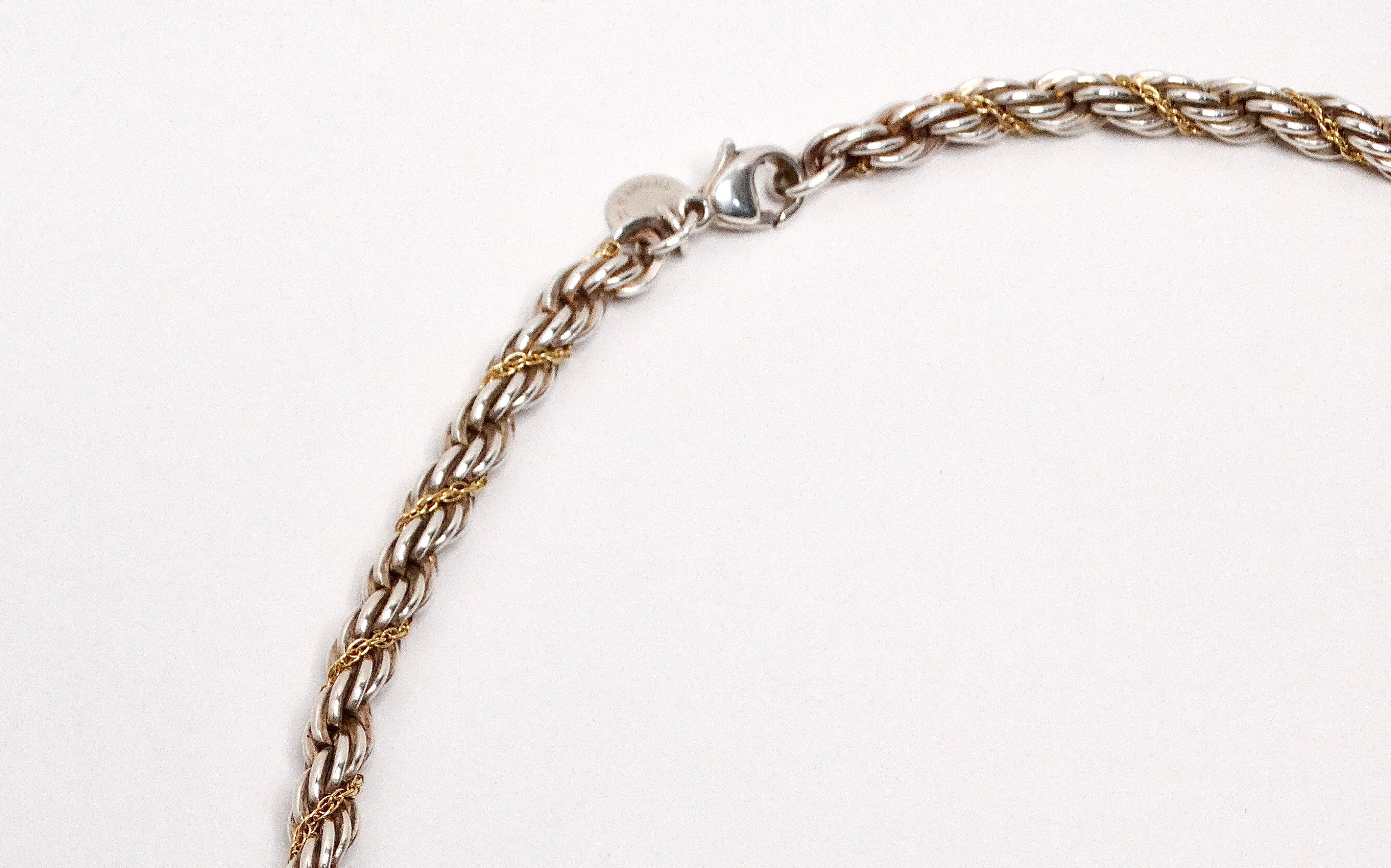 The Tiffany & Co. Rope Chain Sterling Silver and 14K Gold Necklace is a beautiful fusion of classic and contemporary design elements. This necklace features a sterling silver and a 14k gold rope chain, known for its twisted, textured pattern that