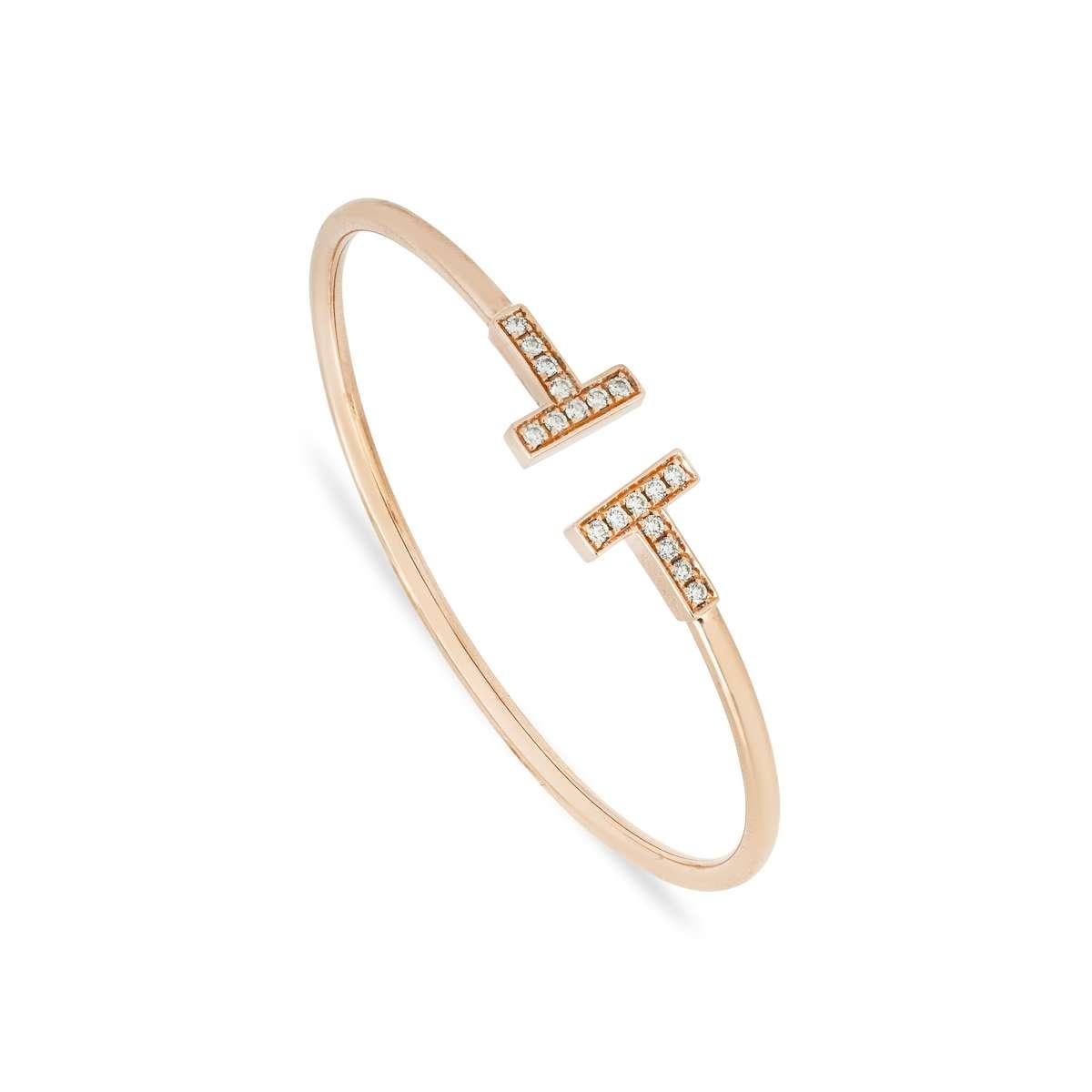 A timeless 18k rose gold diamond bracelet by Tiffany & Co. from the Tiffany T collection. The bracelet comprises of two iconic Tiffany T motifs in a cuff style, pave set with 18 round brilliant cut diamonds with an approximate weight of 0.24ct, F-G