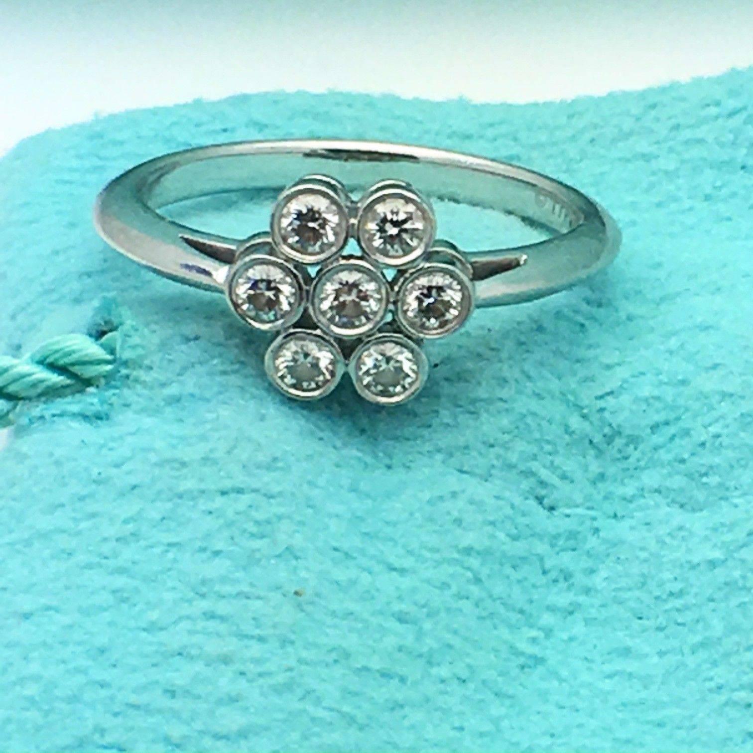Tiffany & Co.
Style:  Bezel Set Flower Diamond Ring
Metal:  Platinum PT950
Size:  6 - sizable
Total Carat Weight:  0.30 TCW
Diamond Shape:  Round Brilliant Diamonds ( 7 Stones )
Diamond Color & Clarity:  F  / VVS
Hallmark:  ©TIFFANY&CO.