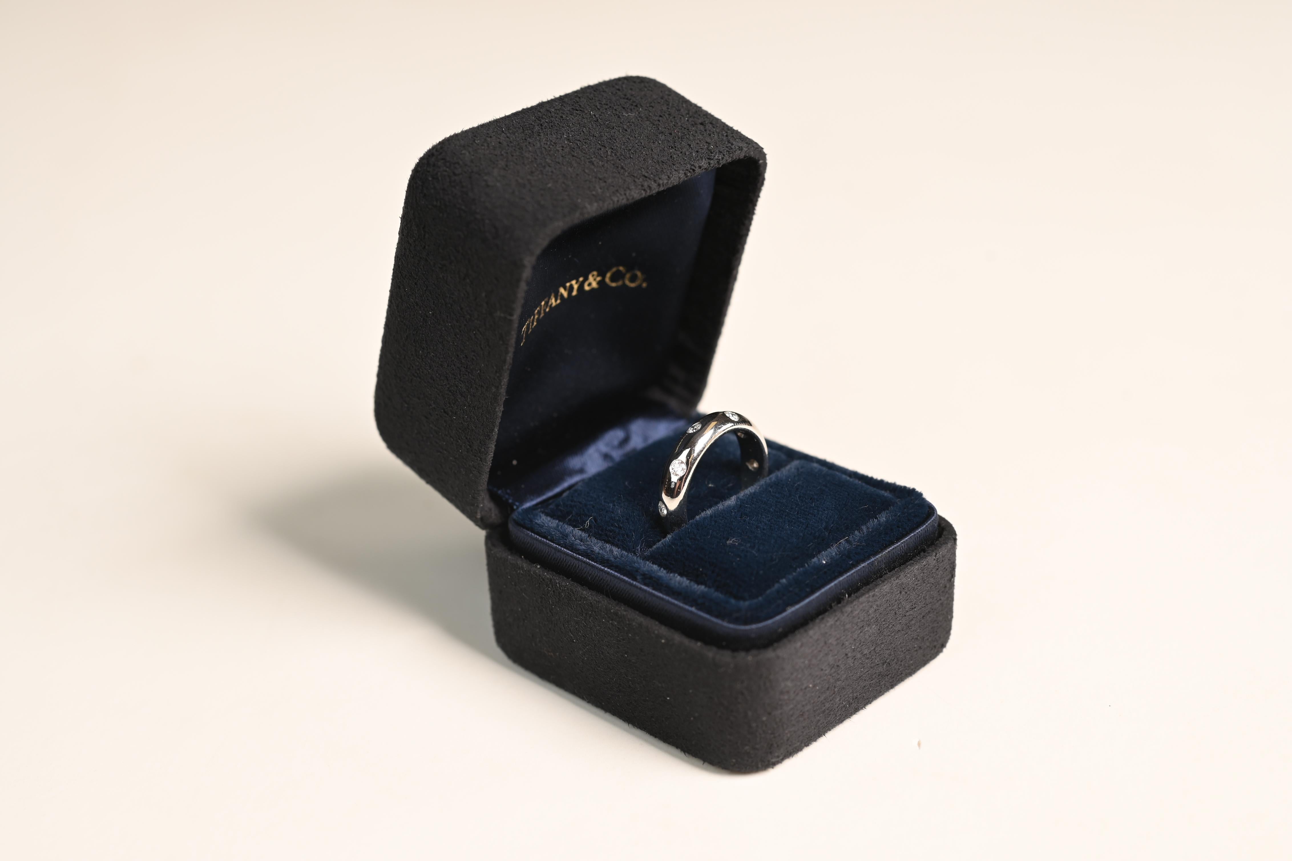 This exquisite Tiffany & Co. diamond band showcases a timeless elegance, crafted in luxurious platinum. Featuring a series of round brilliant-cut diamonds, each bezel-set along the length of the ring, this piece radiates understated sophistication.