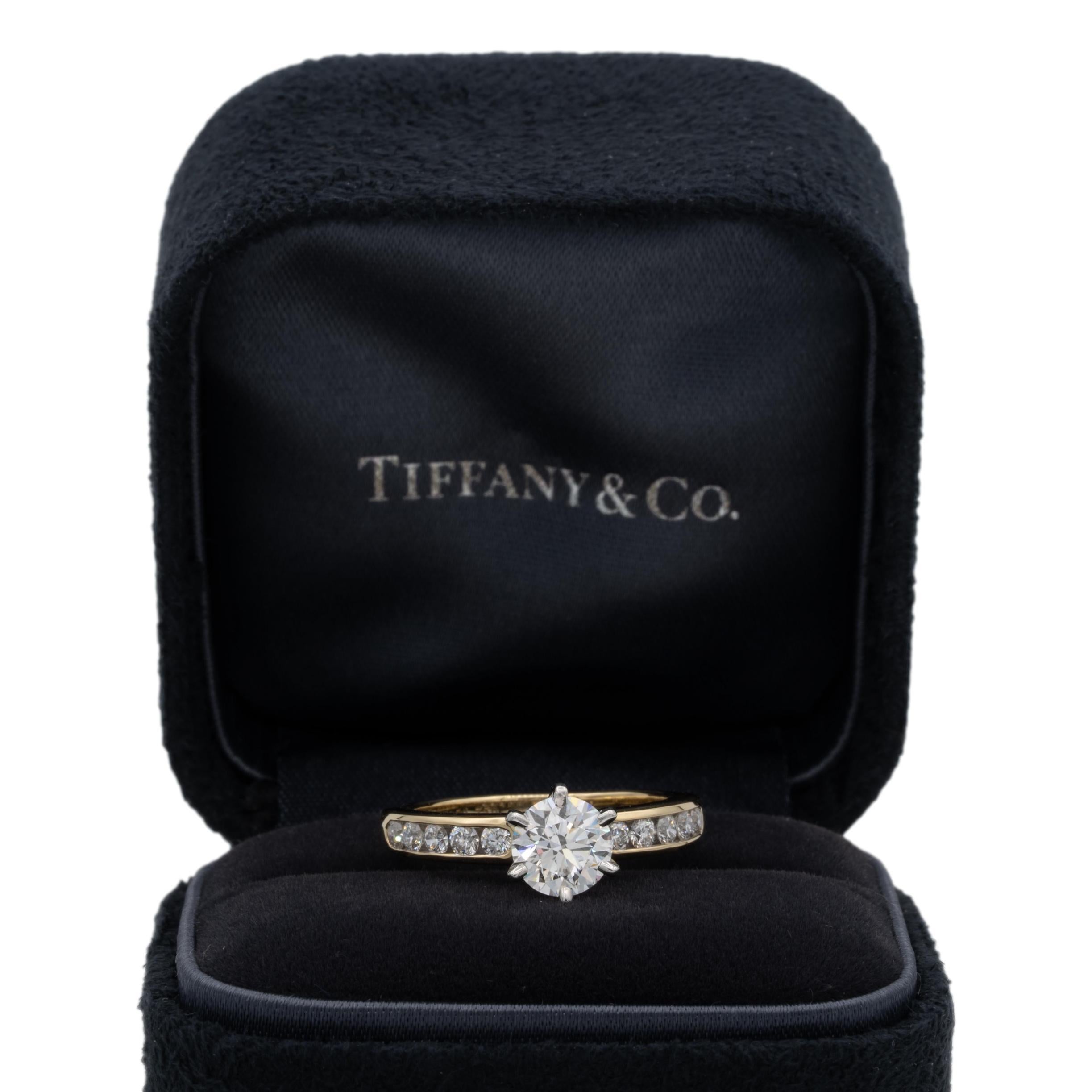 Tiffany & Co. Diamond Engagement ring with channel set diamond band featuring a 0.94 ct center F VVS2 finely crafted in 18 karat yellow gold and platinum prongs. Center diamond is flanked by 5 channel set round brilliant cut diamonds on each side
