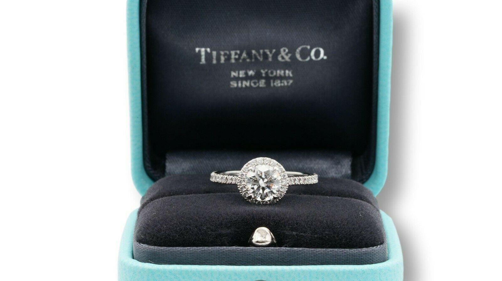 Tiffany & Co. Soleste Diamond Engagement ring featuring a 0.90 ct Round Shape Center diamond finely crafted in Platinum graded E color and VVS2 clarity with Tiffany certificate #62335483, accented by a bead set diamond halo and shank with 42 round