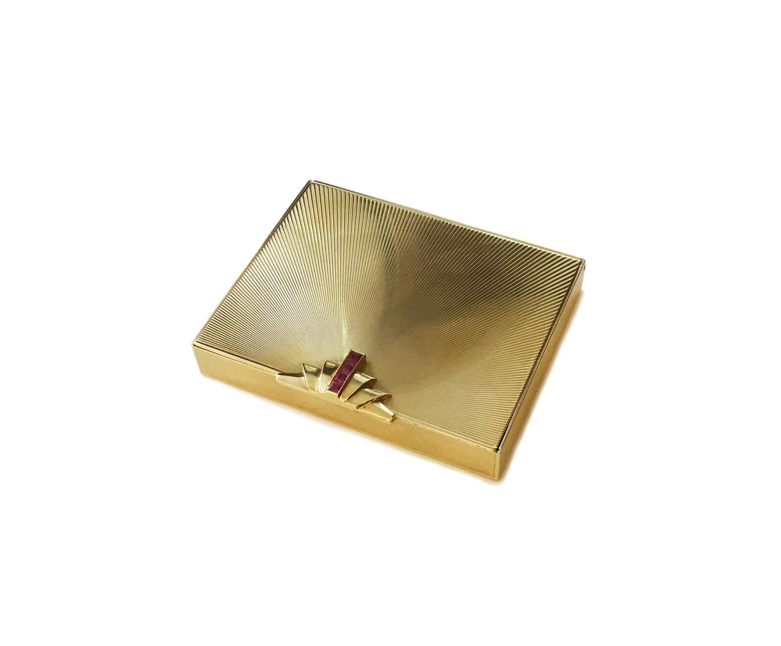 A stunning Retro compact from Tiffany & Co. The compact is made from 14kt solid yellow gold. The face of this compact has a simple design that holds four vibrant, square-cut rubies. The exterior has a carved texture which perfectly represents the
