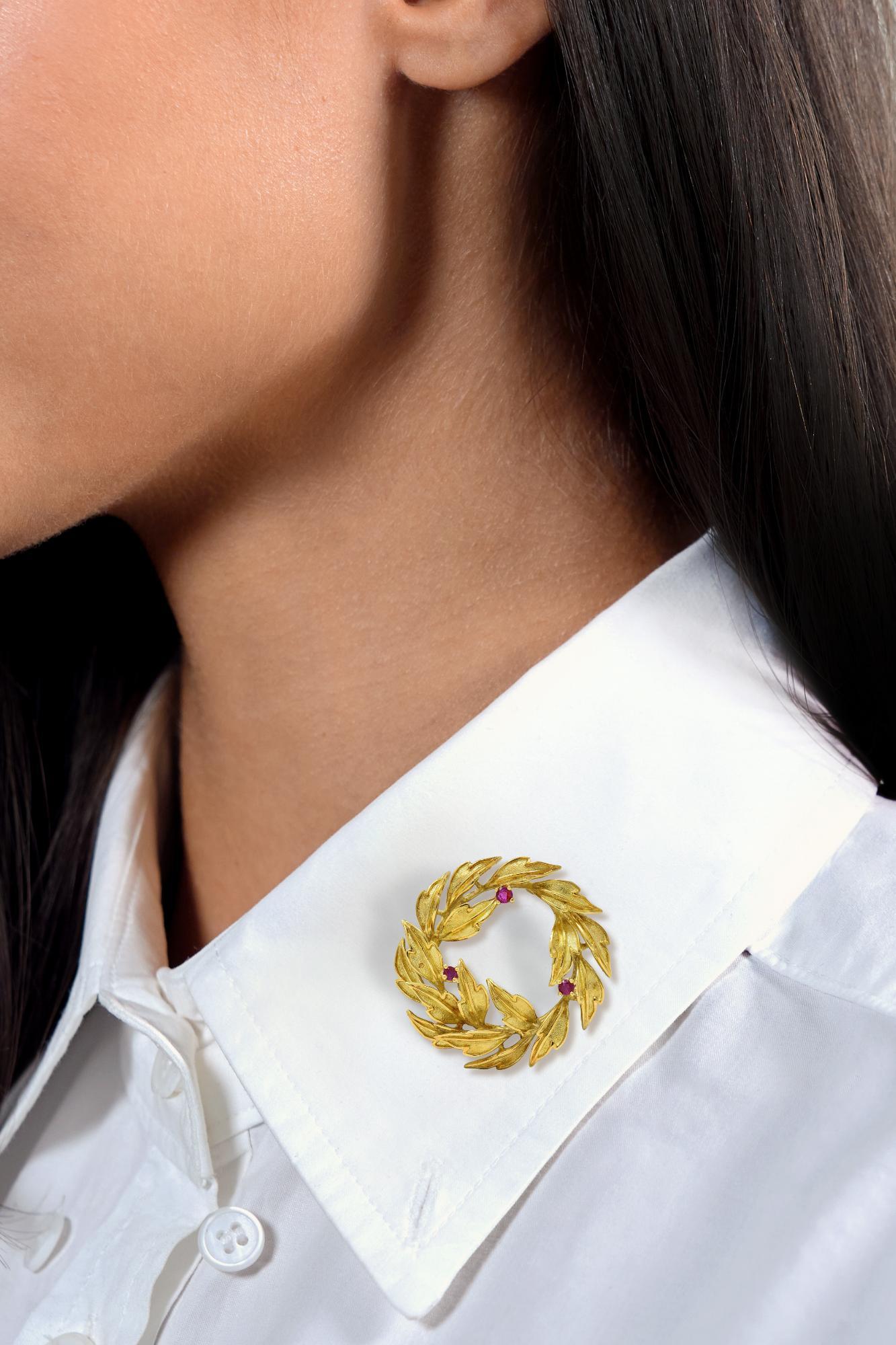 Entworfen als kreisförmiger Kranz aus abgestuften, dimensionalen Blättern
Mit strukturierten Zentren und hochglanzpolierten Kanten und Adern
Akzentuiert durch rund geschliffene Rubine in Zackenfassung
Mit einem Gesamtgewicht von etwa 0,25