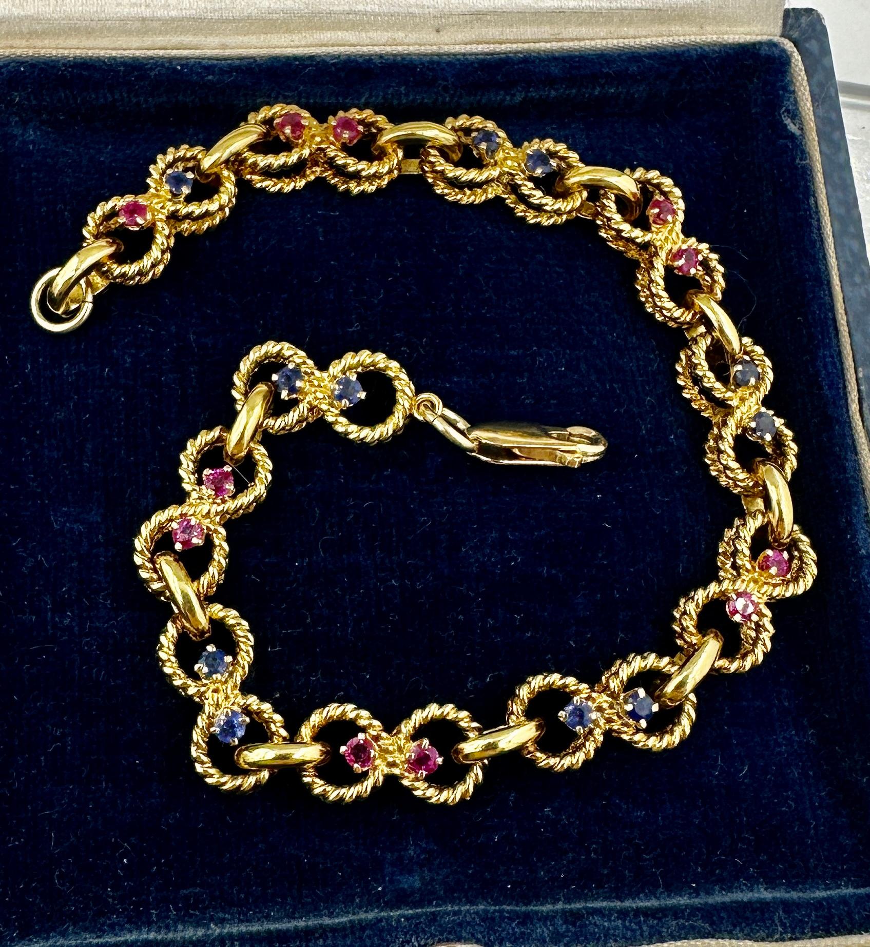 Se trata de una impresionante antigüedad de Tiffany & Co. Pulsera de rubíes y zafiros en oro amarillo de 14 quilates firmada por Tiffany & Co.  La antigua pulsera vintage Tiffany está engastada con parejas de rubíes y zafiros redondos en eslabones
