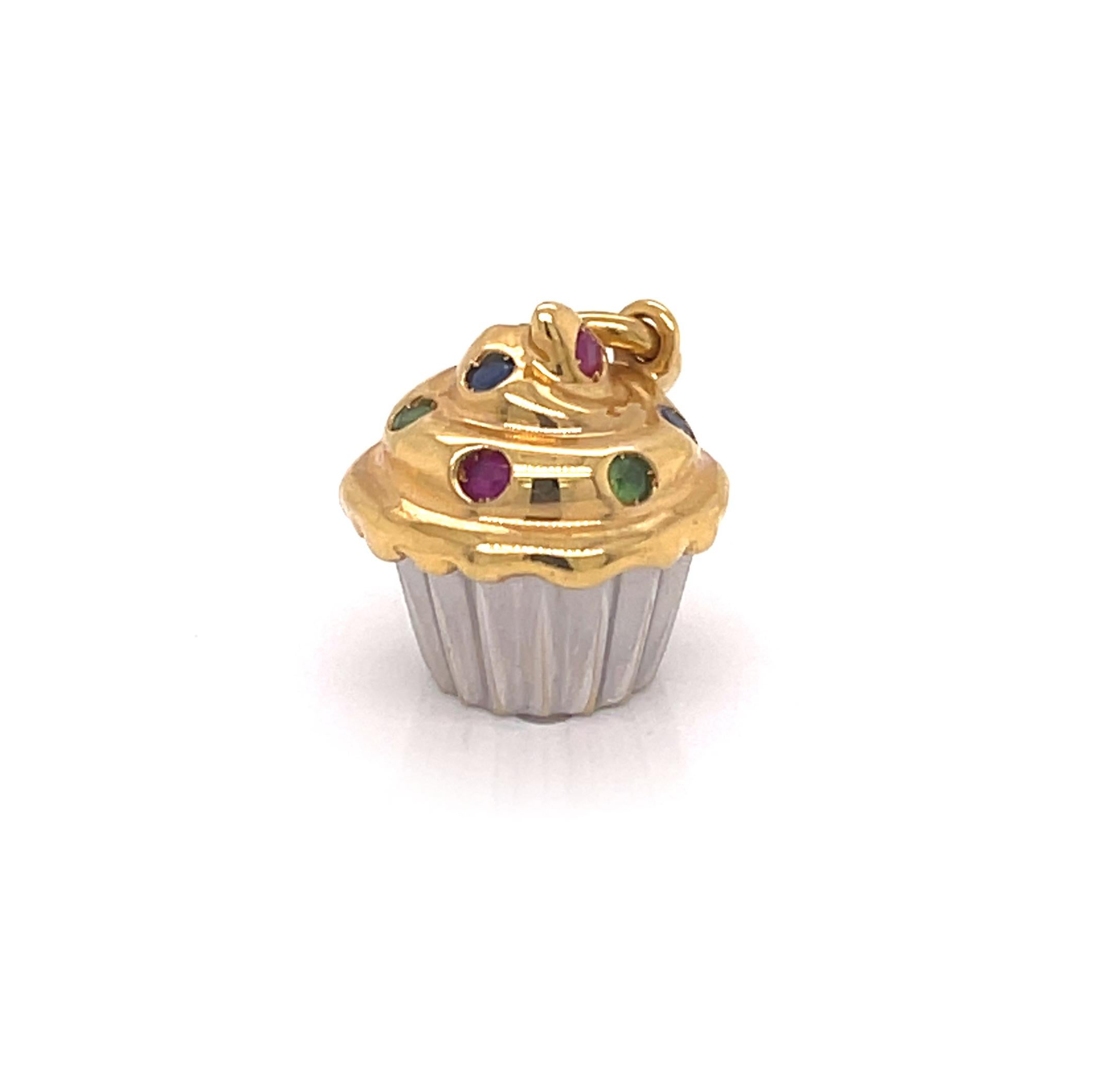 This is an appetizing authentic cupcake charm from Tiffany & Co. It is crafted from 18k yellow and white gold with a polished finish featuring yellow gold frosting at the top with gemstone sprinkles, ruby, sapphire and emerald. The fluted shape cup