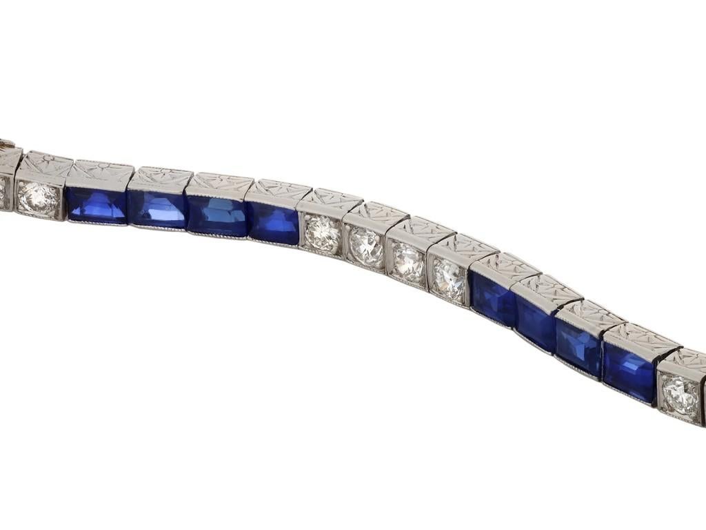 Tiffany & Co. sapphire and diamond line bracelet. Set with twenty four rectangular step cut natural unenhanced sapphires in open back half rubover settings with a combined approximate weight of 4.80 carats, further set with twenty five round old cut