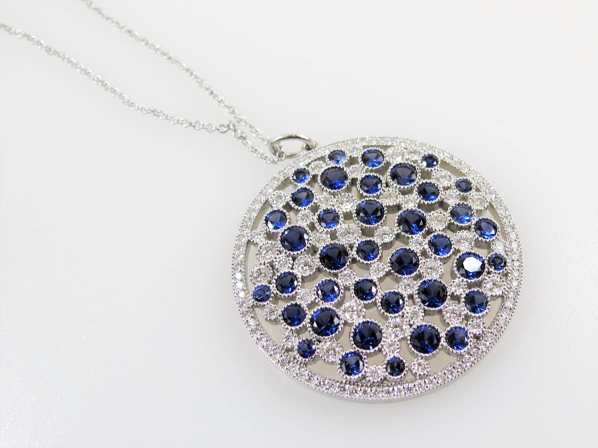 This is an absolutely stunning, brightly colored Cobblestone medallion necklace by renowned jewelry retailer, Tiffany & Co. Featuring luxurious sapphire gemstones paired with incredible, icy white diamonds, this pendant is bursting with playful