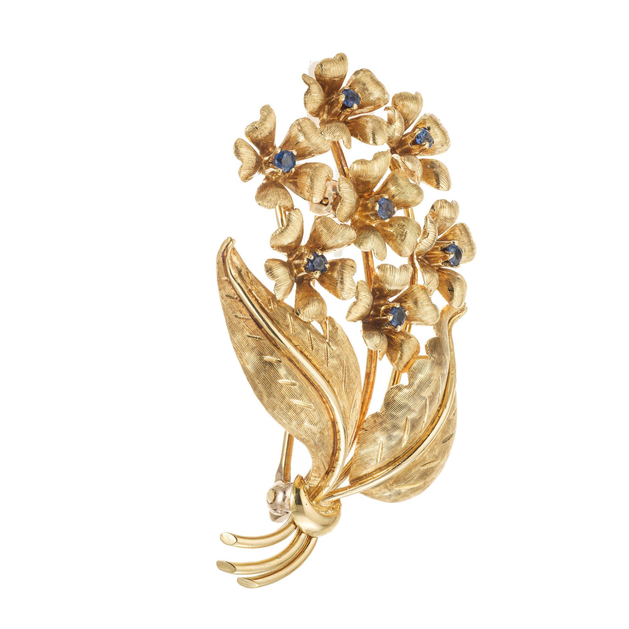 Broche saphir Tiffany & Co texturée à la main. 7 saphirs bleus ronds sertis dans des fleurs en or jaune 18k. Vers les années 1950.

7 saphirs authentiques bleu vif, poids total approx. 0,21 ct, 1,5 mm
9.5 grammes
or jaune 18k
Estampillé : Tiffany &