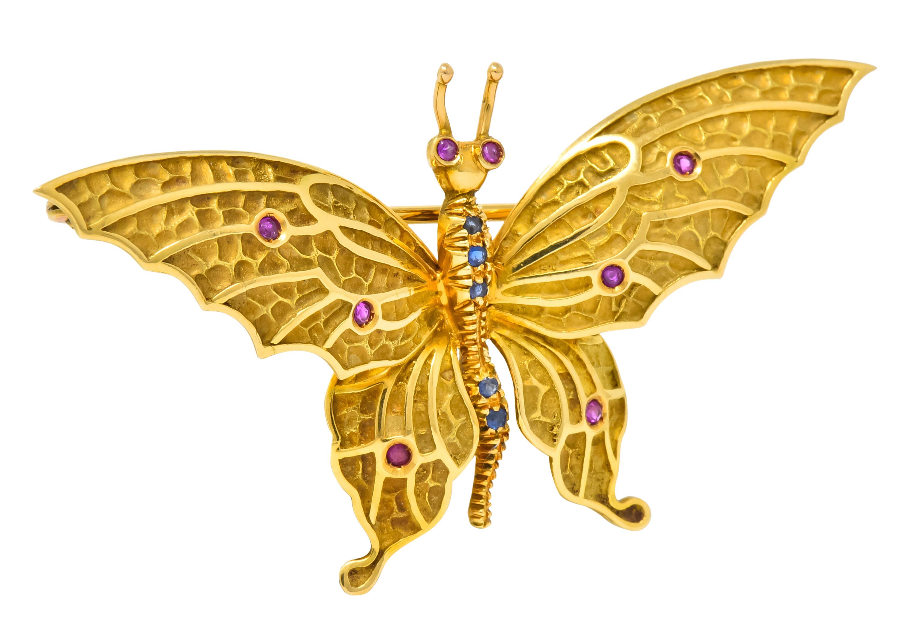 Brooch designed as a butterfly featuring matte green gold repoussé wings with high polished edges

With textured ribbed body and whimsical antennae

Accented by round cut rubies and sapphires throughout, translucent and brightly colored

Completed