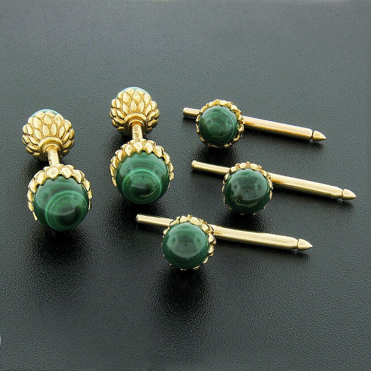 This gorgeous set of Tiffany & Co. cuff links and button stud set is designed by Schlumberger and crafted in solid 18k yellow gold. They feature the iconic Acorn design and are set with round bead, natural genuine malachite stones. The panels are