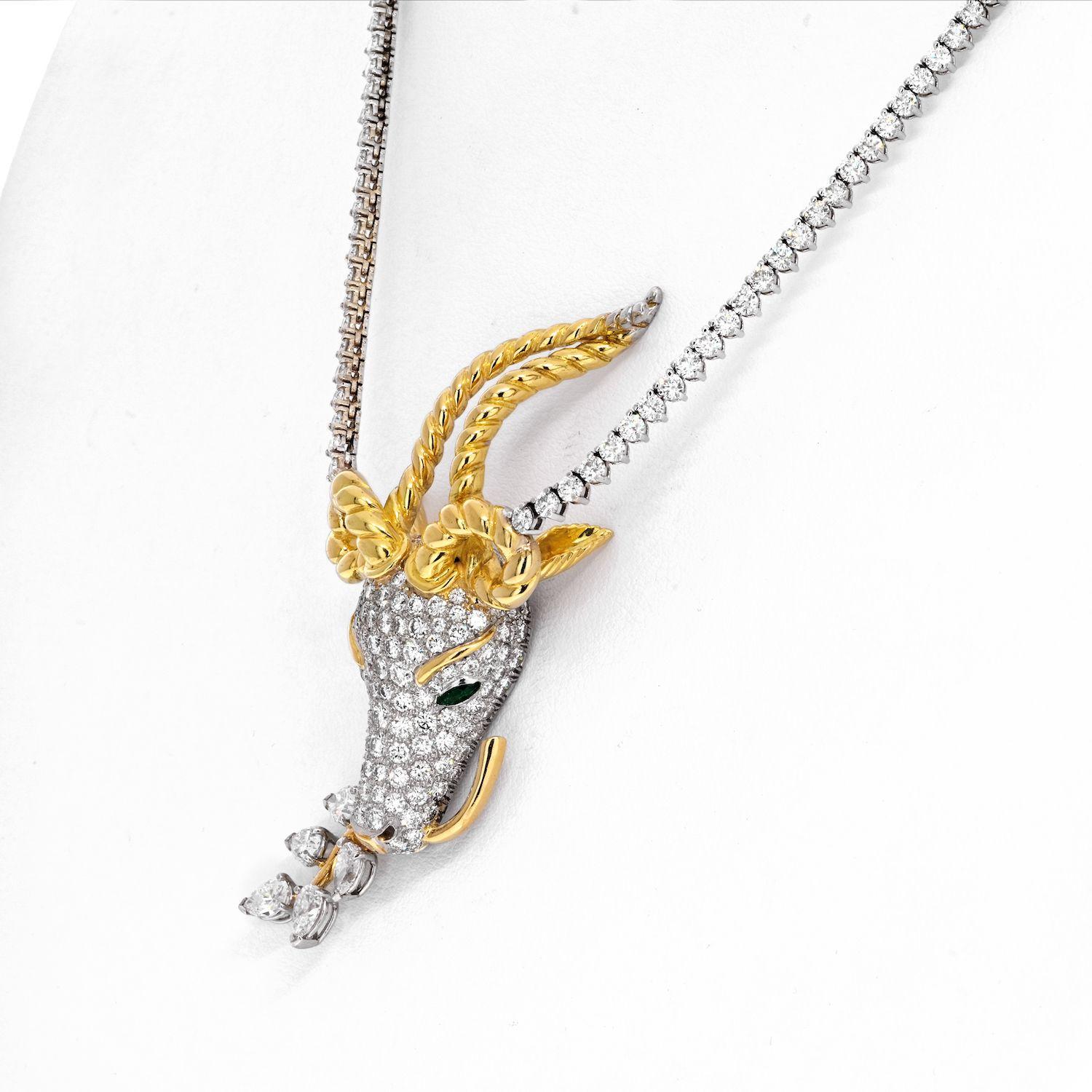 The pavé-set diamond head features haunting, marquise green emerald eyes and supports two delicately twisting gold antlers and textured ears. The gazelle carefully holds a gold and pear-shaped diamond branch of leaves in its mouth. Platinum ad 18k