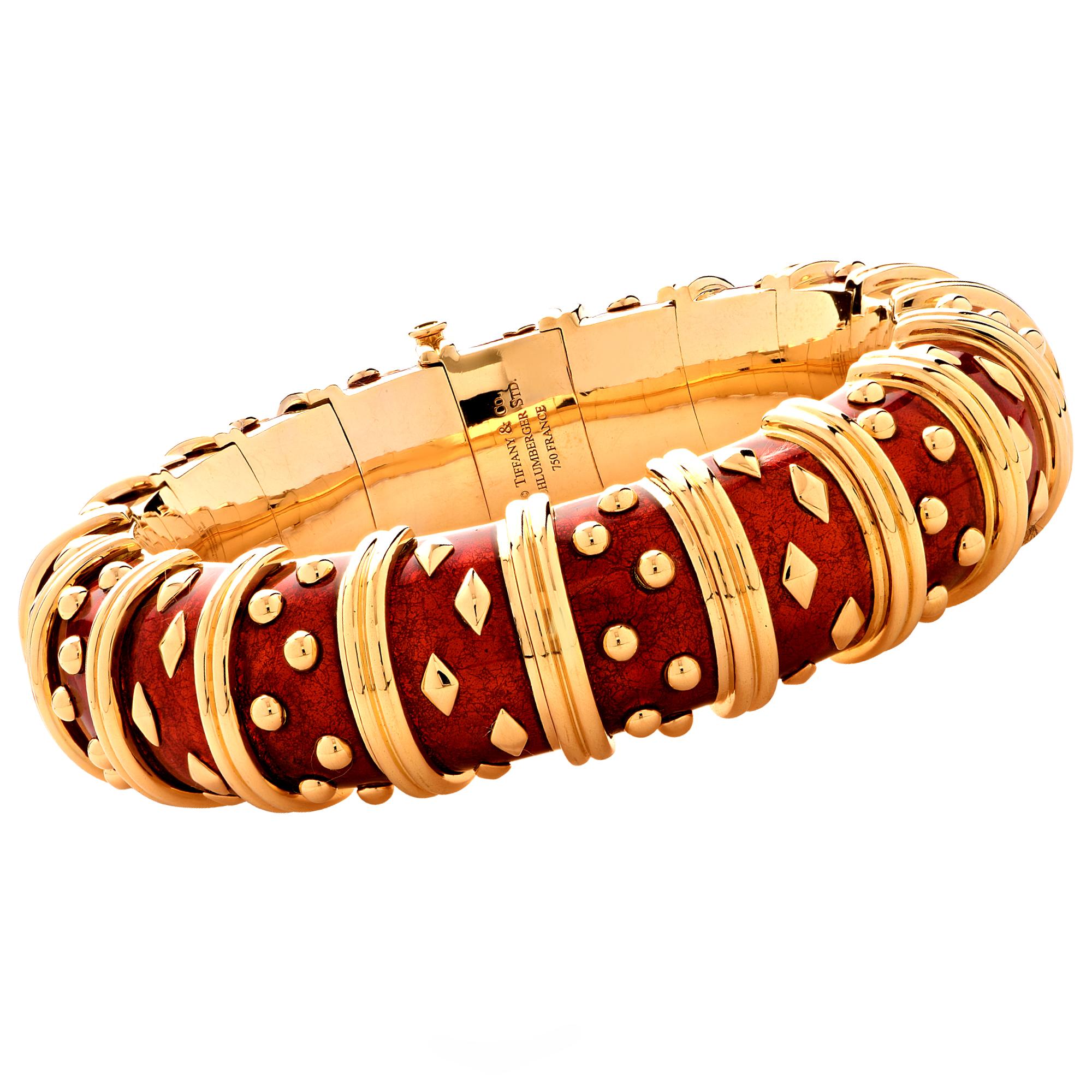 Stunning Tiffany & Co. Schlumberger Dot Losange Bracelet, crafted in 18k yellow gold and enriched with vibrant crimson red enamel, accented with alternating clusters of gold dots and diamond shapes, separated by gold rings. The bracelet measures .7