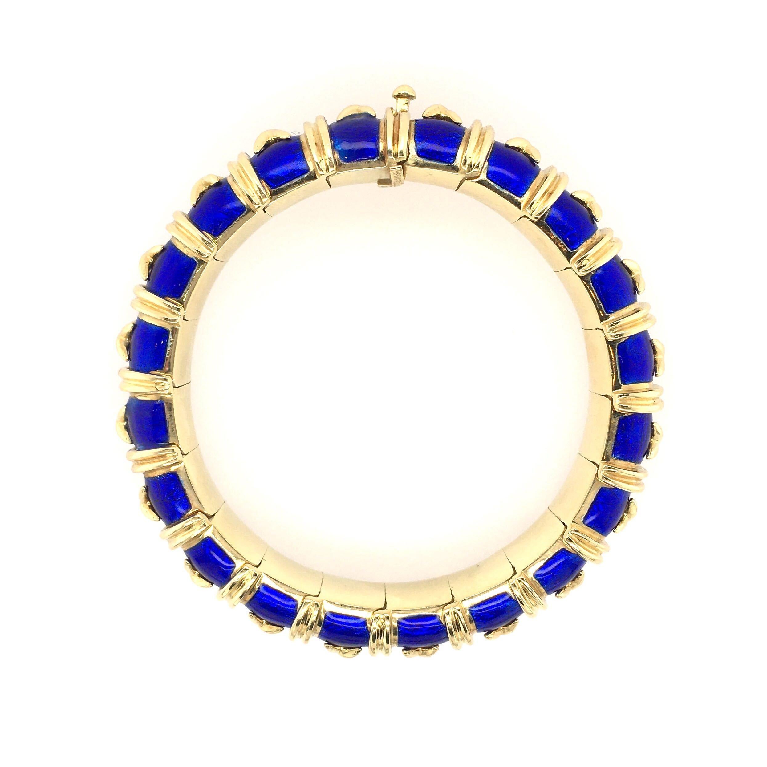An 18 karat yellow gold and blue enamel Croisillon bracelet.  Signed Tiffany & Co Schlumberger.  Made in France. The royal blue paillonné enamel articulated bangle with applied cross-shaped gold details and reeded band spacers, inner circumference