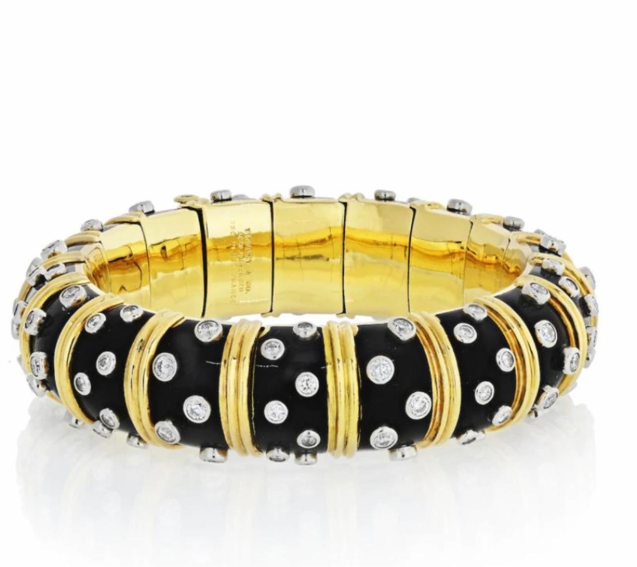 A DIAMOND AND BLACK ENAMEL BANGLE BRACELET, BY JEAN SCHLUMBERGER, TIFFANY & CO.
Designed as a Black paillonné enamel hinged bangle, decorated with collet-set diamonds and sculpted gold vertical bands, 6 3/4 ins. inner diameter, mounted in platinum
