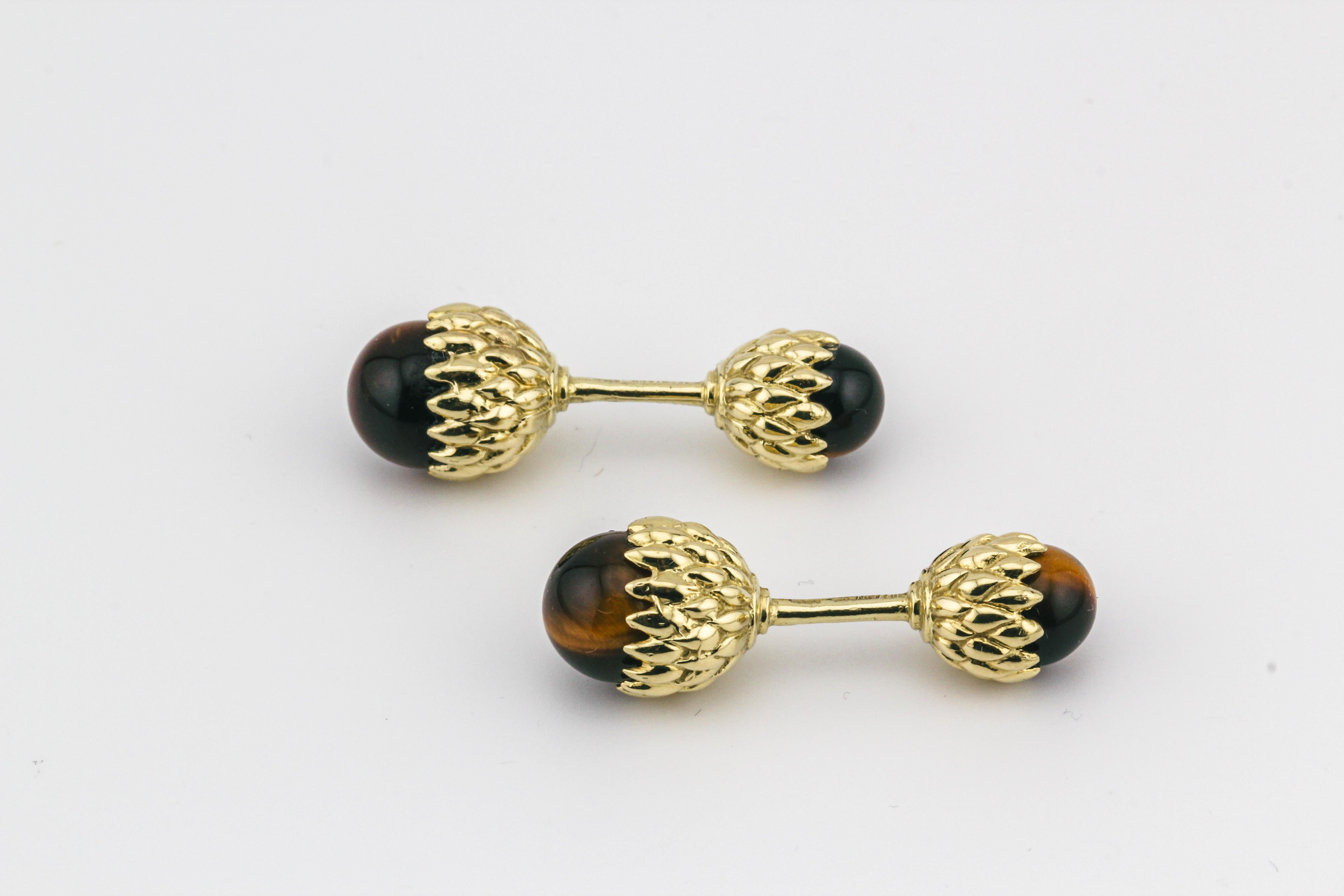 Immerse yourself in the world of opulence and distinctive style with the Tiffany & Co. Schlumberger Tiger's Eye 18K Yellow Gold Acorn Cufflinks. A harmonious blend of nature-inspired design and luxurious craftsmanship, these cufflinks stand as a