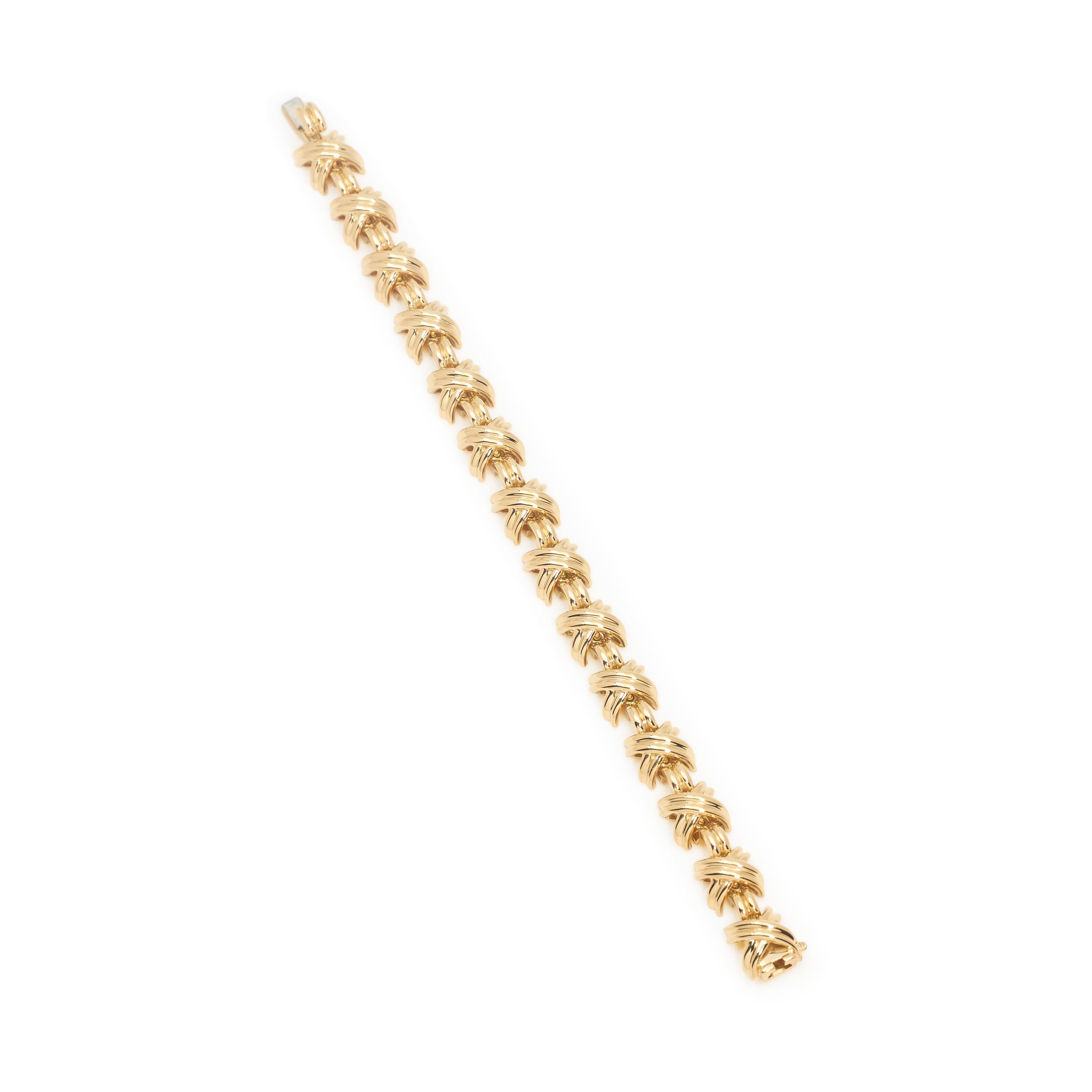 Authentique bracelet Tiffany & Co. réalisé en or jaune 18 carats poli et doté des maillons en X caractéristiques de la marque.  Le bracelet mesure 7 1/2 pouces de longueur totale et 10.6mm de largeur.  Signé T&Co, 750, avec des poinçons.  Le