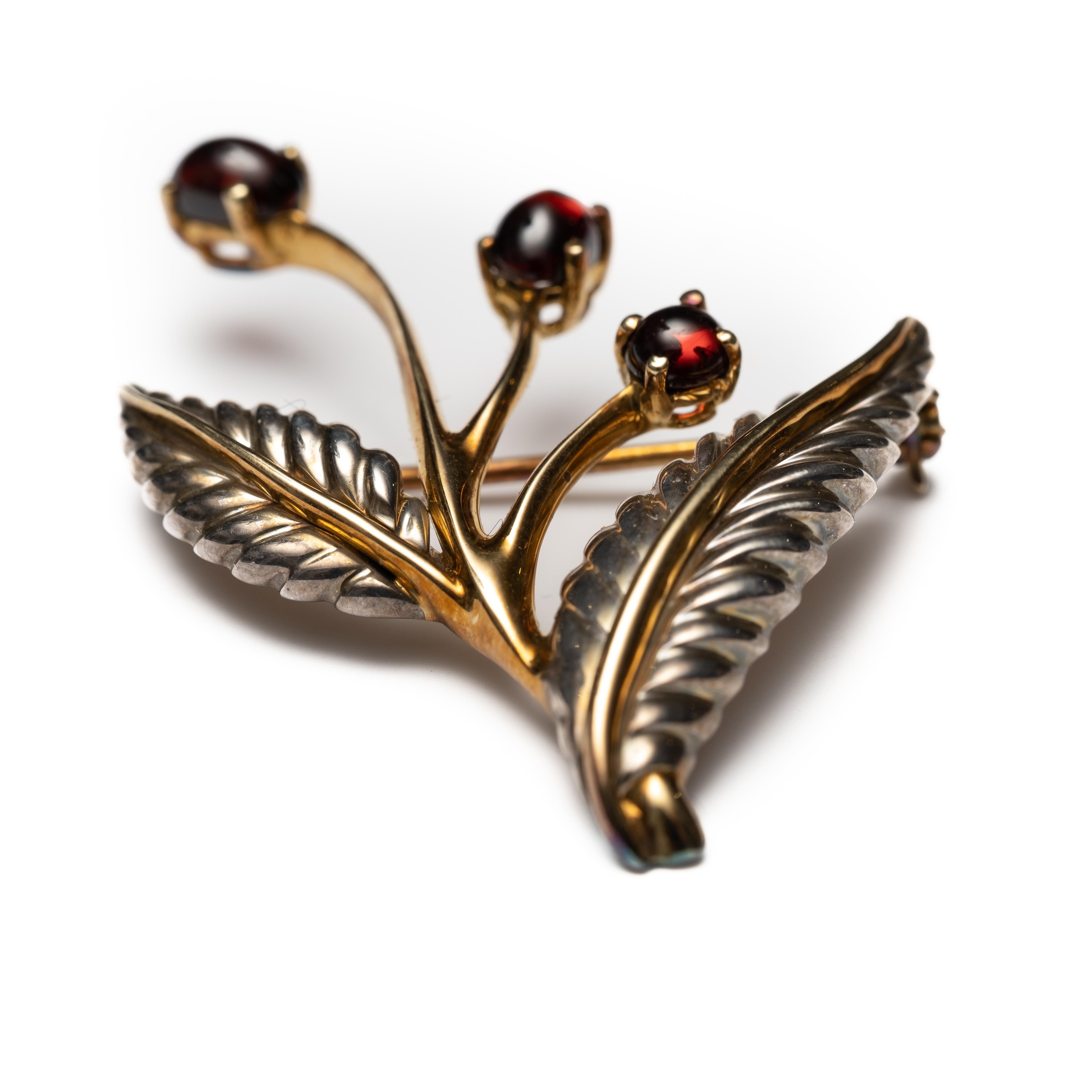 Tiffany and Co 18k Gold, silver and rhodolite garnet brooch, in the original box. The garnets are set in 18 Karat Gold stems. The leaves of the flower are Sterling Silver with 18 Karat Gold centers. Circa 2006. In consultation with Tiffany and Co,