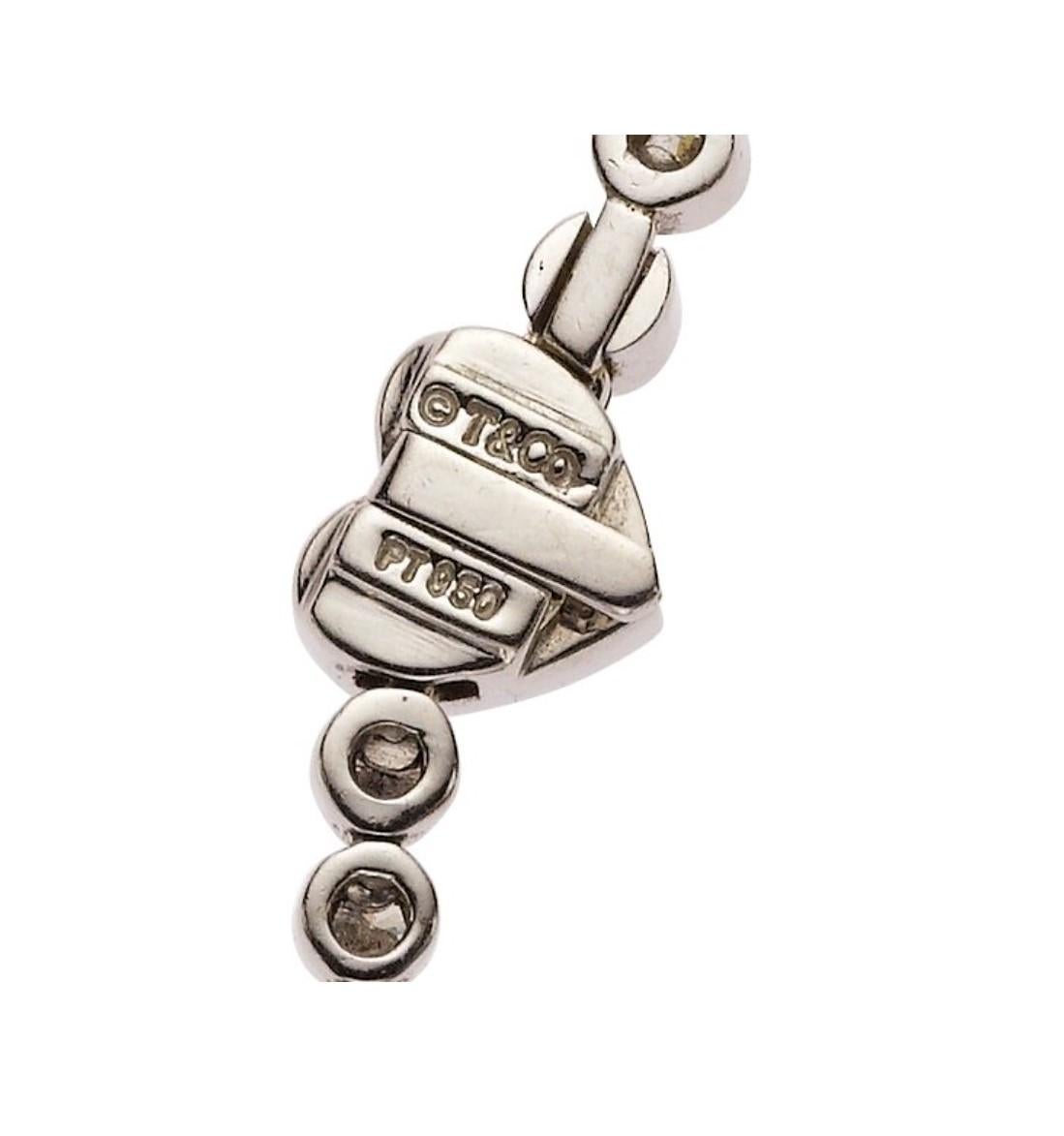 This platinum necklace by Tiffany & Co. features approximately 5.45 carats of full-cut diamonds, set in a classic, bezel-set design. A notable beautiful detail of the piece is it's heart-shaped, tongue and groove clasp. 

The necklace measures 16.25