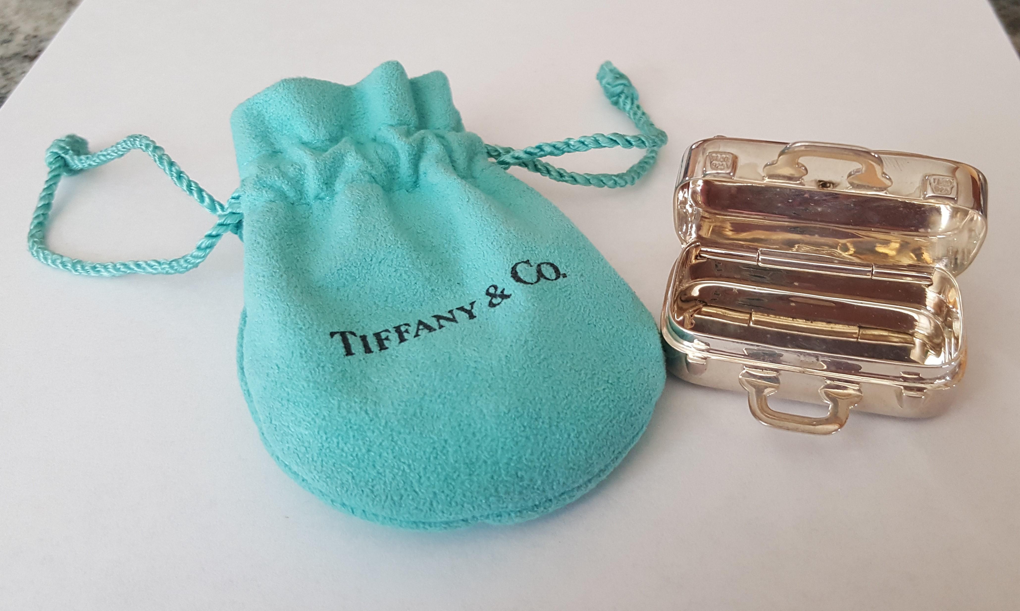 Tiffany Co 925 Silver Pillbox, suitcase luggage that says London, New York, Beverly Hills on one side and Tokyo, Munich, and Honolulu on the other. Not in production anymore, great for a collector.  Gram weight 37.8, dimensions 24mm x 16mm x 44mm.