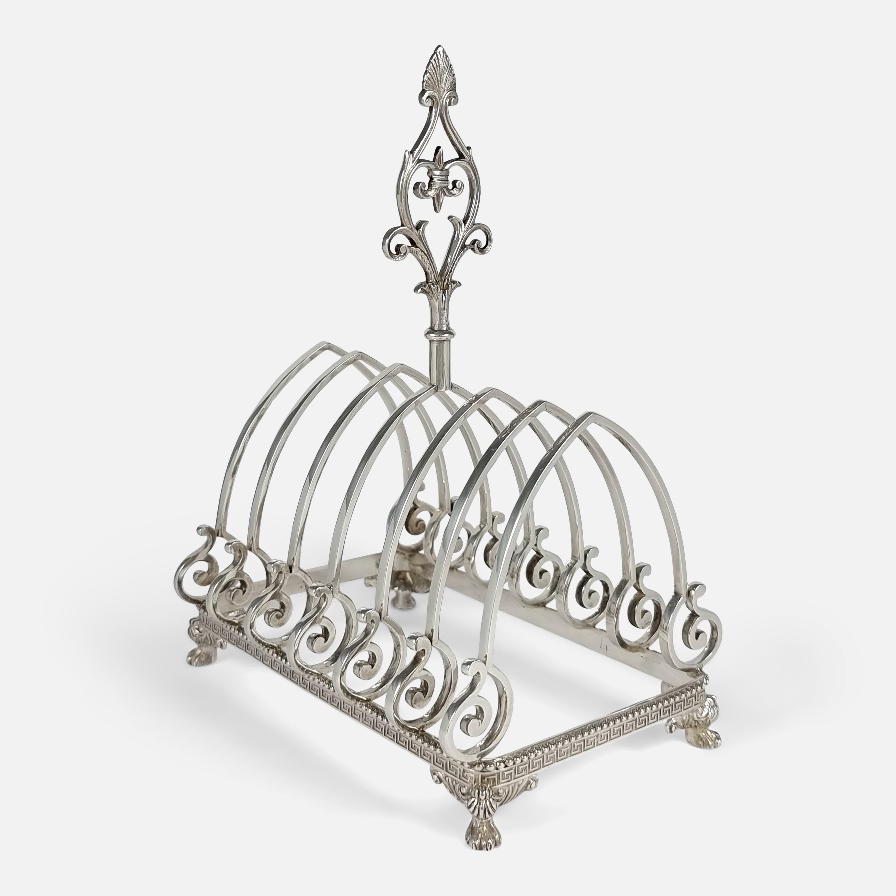 An American silver rectangular toast rack by J.C. Moore & Son for Tiffany & Co. The toast rack is crafted with an anthemion finial to the scroll handle, the seven dividers with arch tops and scroll bases, on a beaded and Greek key base with four
