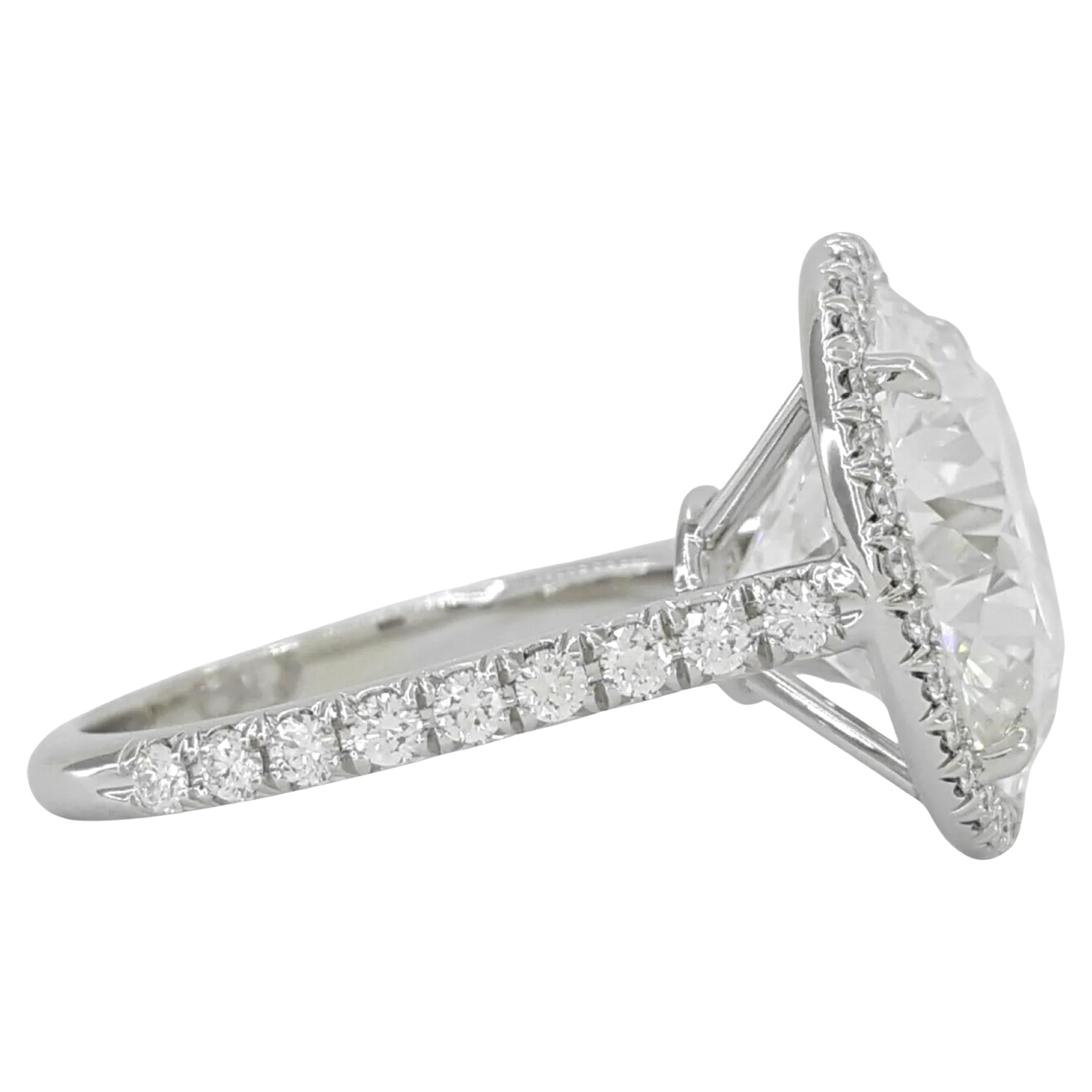 Tiffany & Co. Soleste Round Brilliant Cut Diamond Halo Engagement Ring is an exquisite and substantial piece of fine jewelry. The center stone is an impressive 8.06-carat Natural Round Brilliant Cut diamond, characterized by its E color grade,