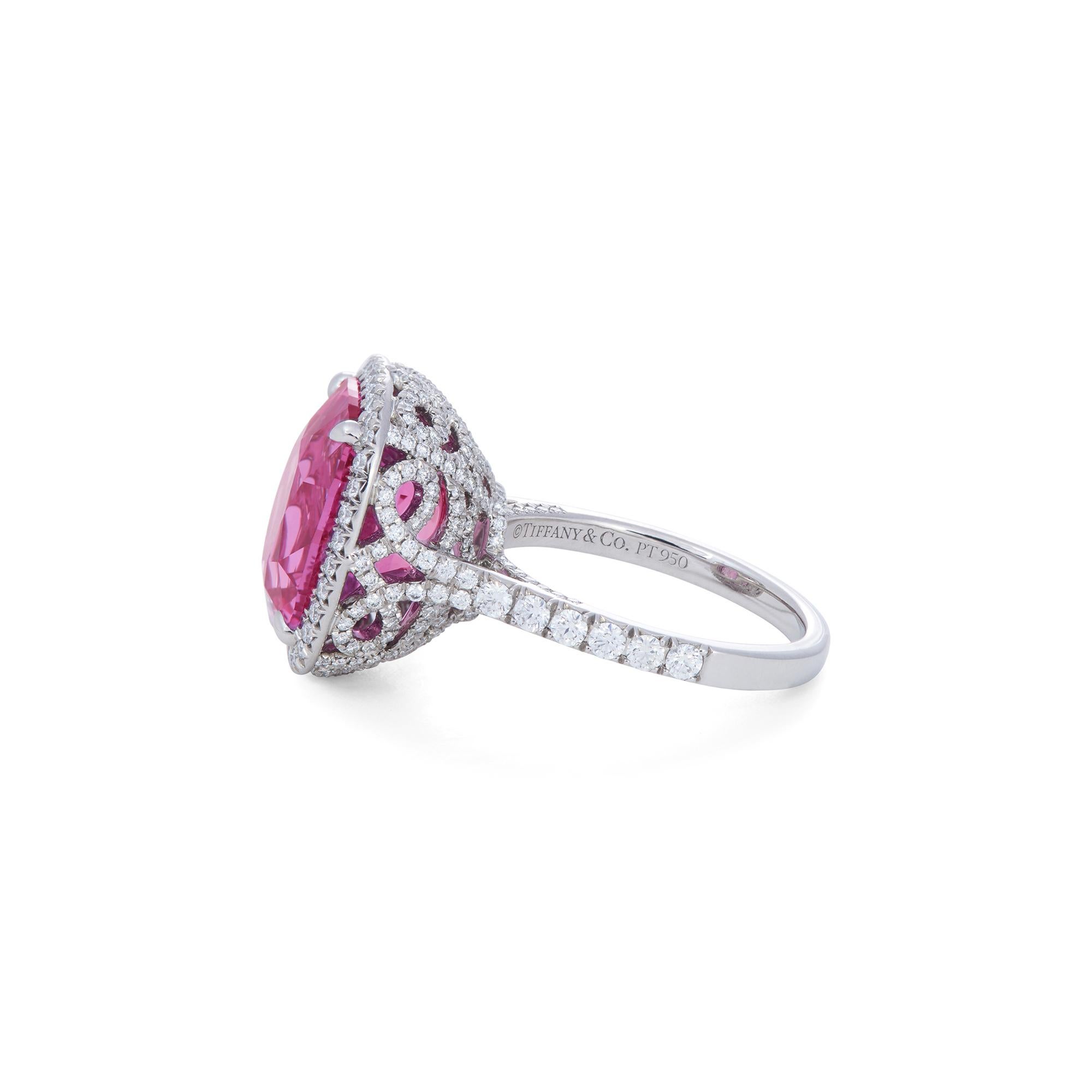 Authentic Tiffany & Co. Soleste ring crafted in platinum.  Featuring an enchanting cushion shaped pink sapphire of approximately 12.69 carats that is surrounded by a halo of round brilliant cut diamonds and situated in an intricately designed