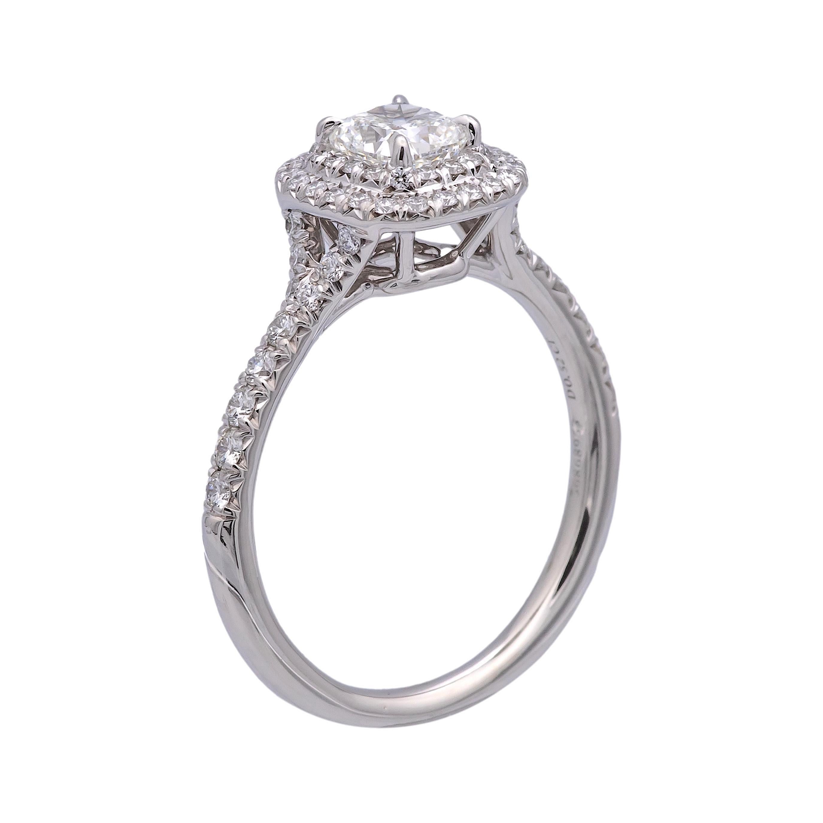 Tiffany & Co. engagement ring from the Novo collection finely crafted in platinum featuring a cushion brilliant diamond center weighing .52 carats , ranging F-G color , VVS2-VS1 clarity set in a 4 prong basket setting accented by a double row halo