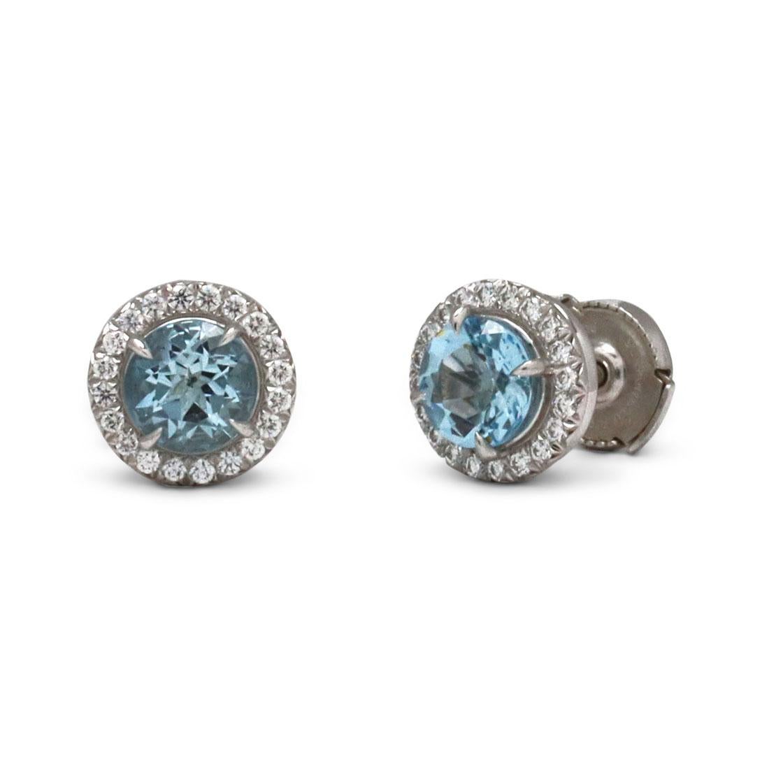 Authentic Tiffany & Co. 'Soleste' earrings each center on a 6mm round aquamarine stone (approx. 1.40cttw) surrounded by high quality round brilliant cut diamonds (approx .40cttw). Signed Tiffany & Co., PT950. The earrings are presented with the