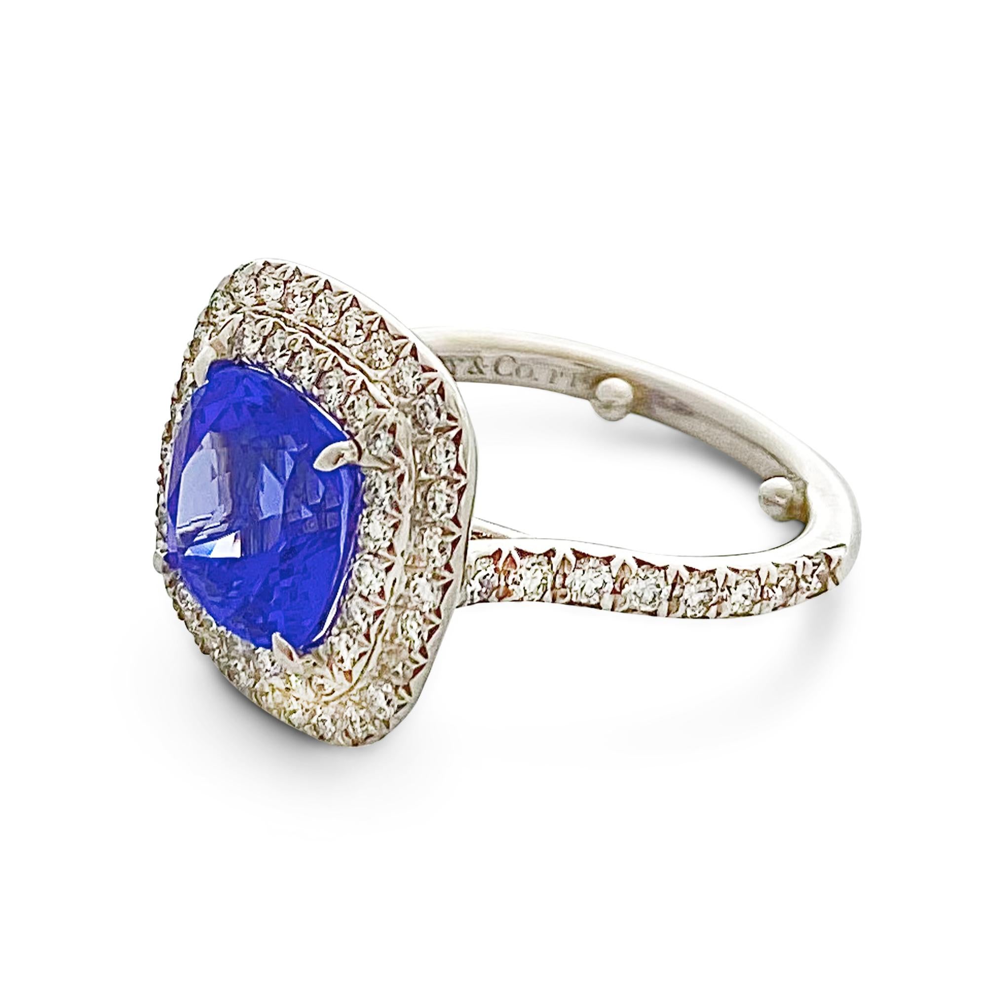 Authentic Tiffany & Co. Soleste ring crafted in platinum.  Centering on a GIA-certified cushion cut tanzanite of 2.45 carats, surrounded by a double halo of glittering round brilliant cut diamonds weighing an estimated .50 carats total.  Size 5 with
