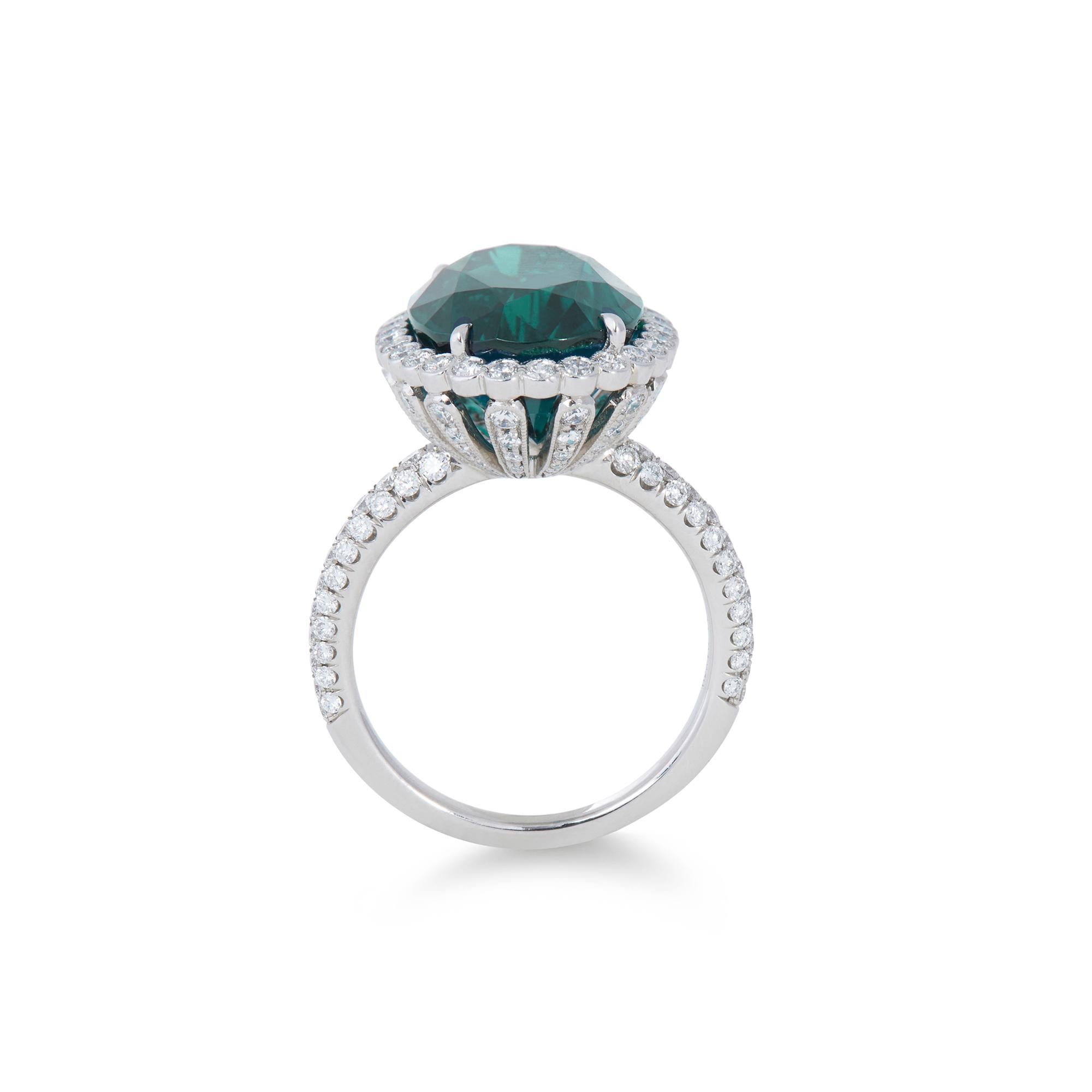 Authentic Tiffany & Co. Soleste ring crafted in platinum.  The ring features a vibrant oval-shaped greenish-blue indicolite tourmaline of approximately 7.5 carats surrounded by a halo of bezel set diamonds and diamond encrusted gallery with fine