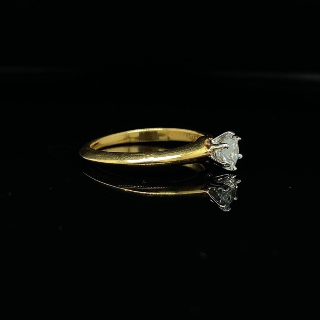 Bague solitaire en diamant Tiffany & Co en or jaune 18 carats 0,42 carat.

La pierre est un diamant rond de taille brillant estimé de couleur H et de pureté VS1 environ.

Cette bague solitaire classique et emblématique 