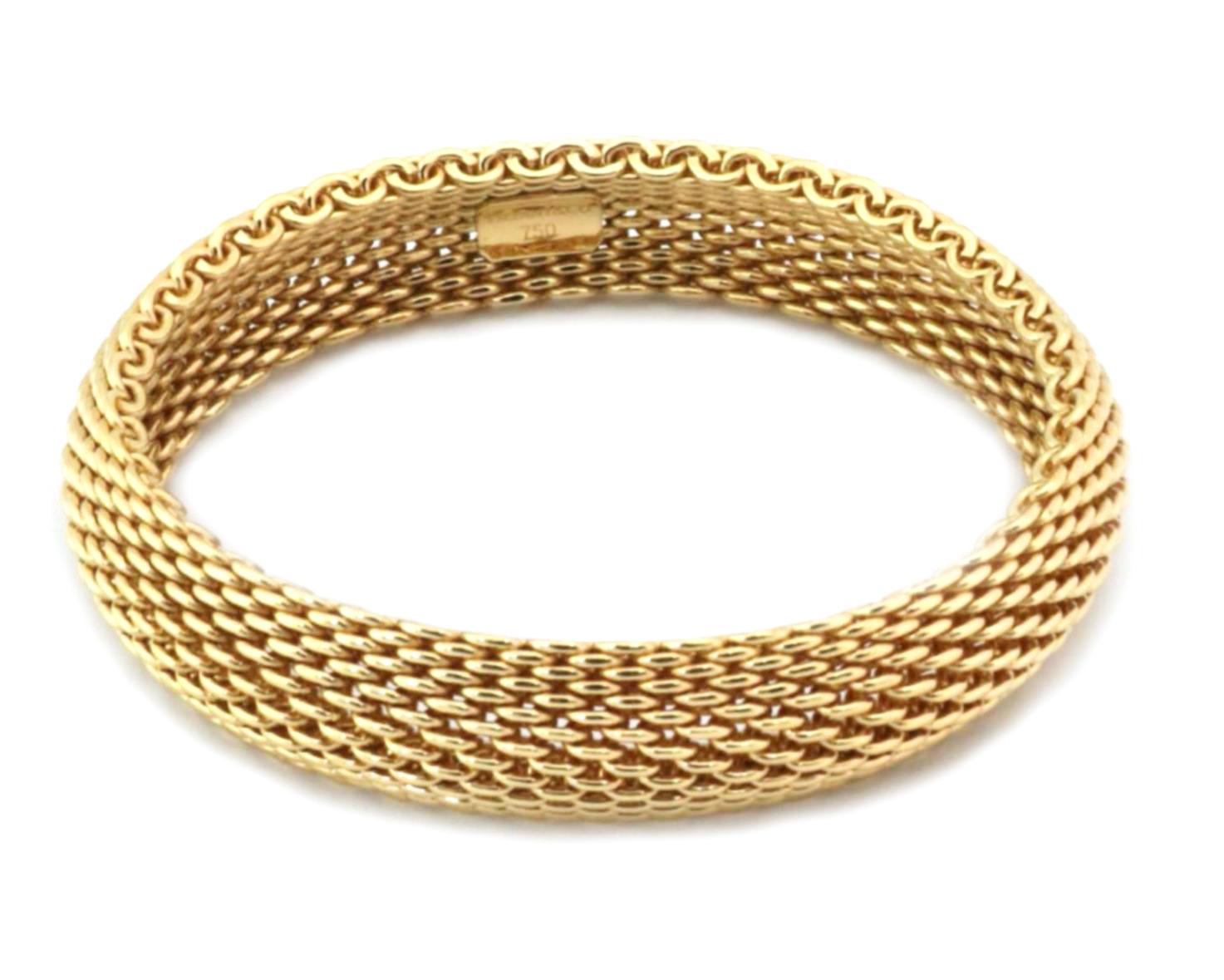 Ce magnifique bracelet authentique de Tiffany & Co. est issu de la collection Somerset. La bande flexible de 15 mm de large est fabriquée en or jaune 18 carats avec une finition polie. Elle porte un poinçon indiquant le nom du créateur et la teneur