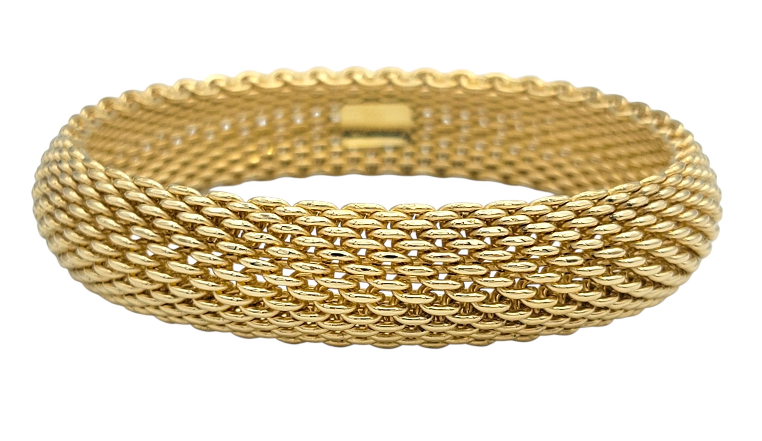 This Tiffany & Co. Somerset mesh bangle is a striking statement of timeless elegance. Crafted in radiant 18 karat yellow gold, its bold mesh design creates a flexible yet substantial silhouette, capturing light from every angle. The wide band
