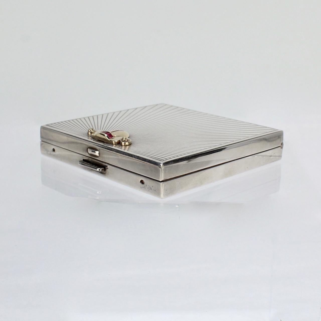 A good, modernist Tiffany & Co sterling, gold, and ruby compact.

Marked to the interior Tiffany & Co.

Marked to the reverse Sterling and with the Thomae Co. factory mark. The gold tests at 14K.

Tiffany retailed these compacts for a number of