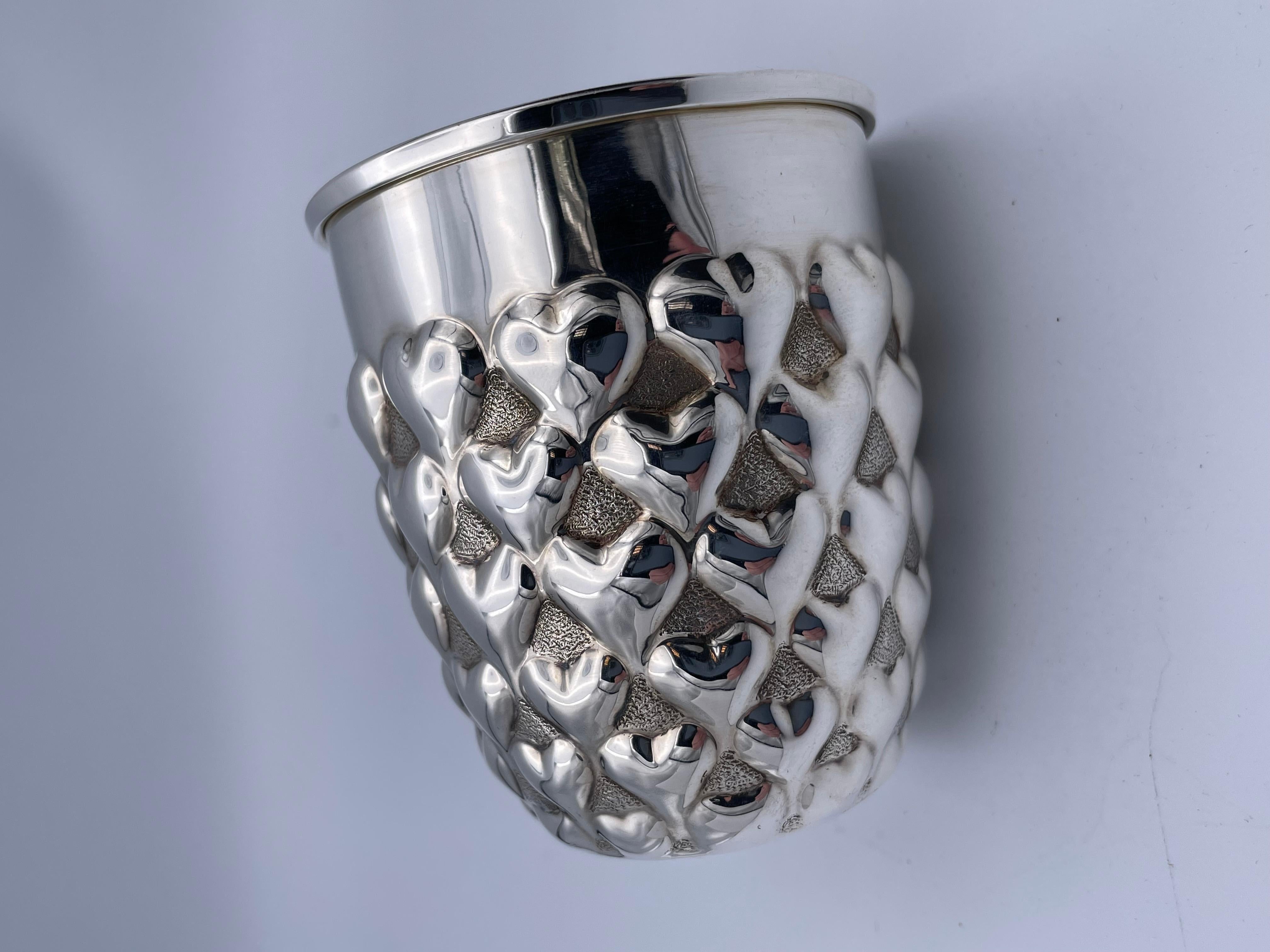 A charming cup, with an allover figural puffed heart design. Made by TIFFANY & CO. Solid gauge sterling silver with a lemon gilt interior. Can be used as a cup or a holder for flowers or a desk container. 2 1/4