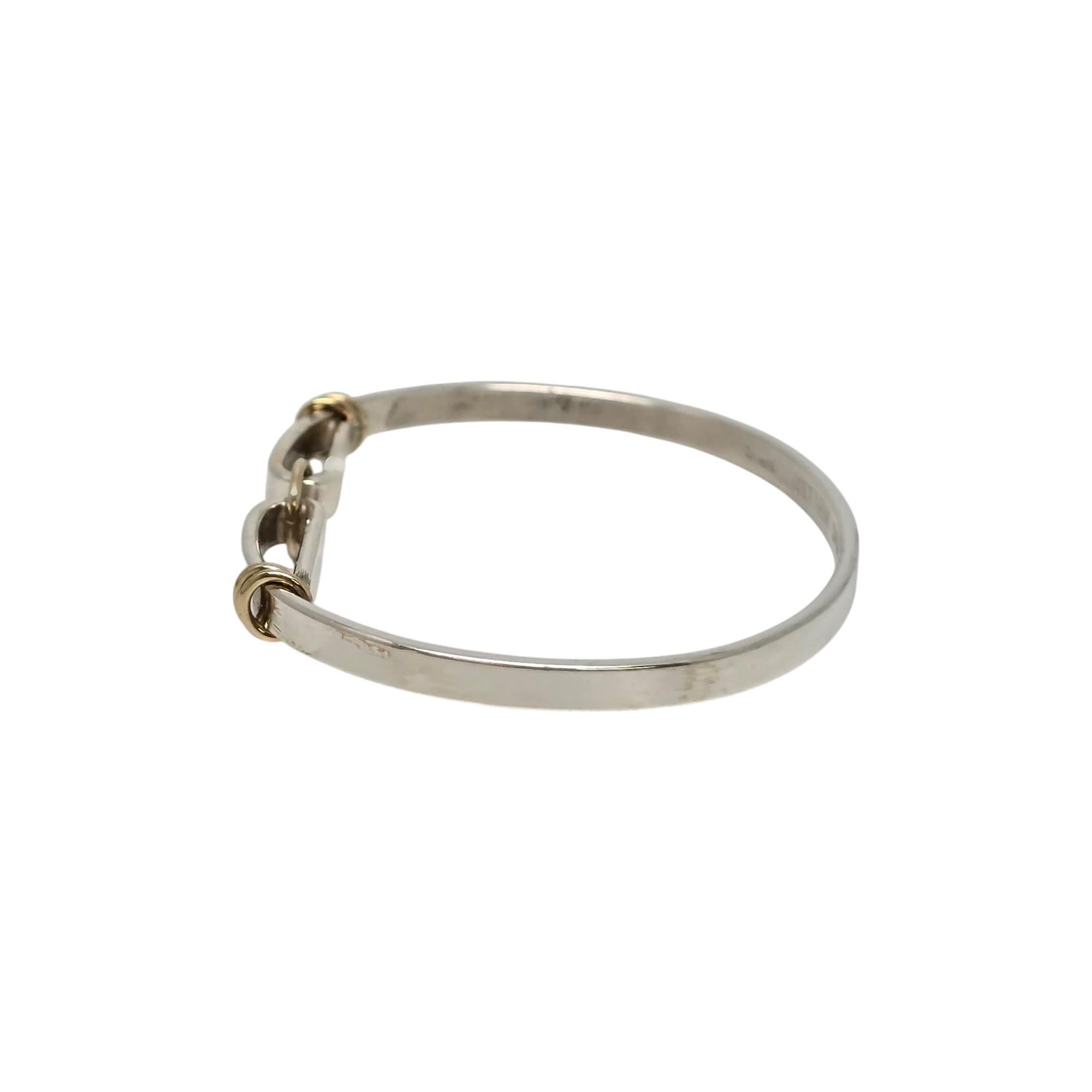 Tiffany & Co sterling silver and 14K yellow gold trim circle hook bangle bracelet.

Authentic Tiffany sterling silver bracelet, 14K yellow gold accent circle as well as gold accent coils on each side. Bangle bracelet opens by unhooking from the