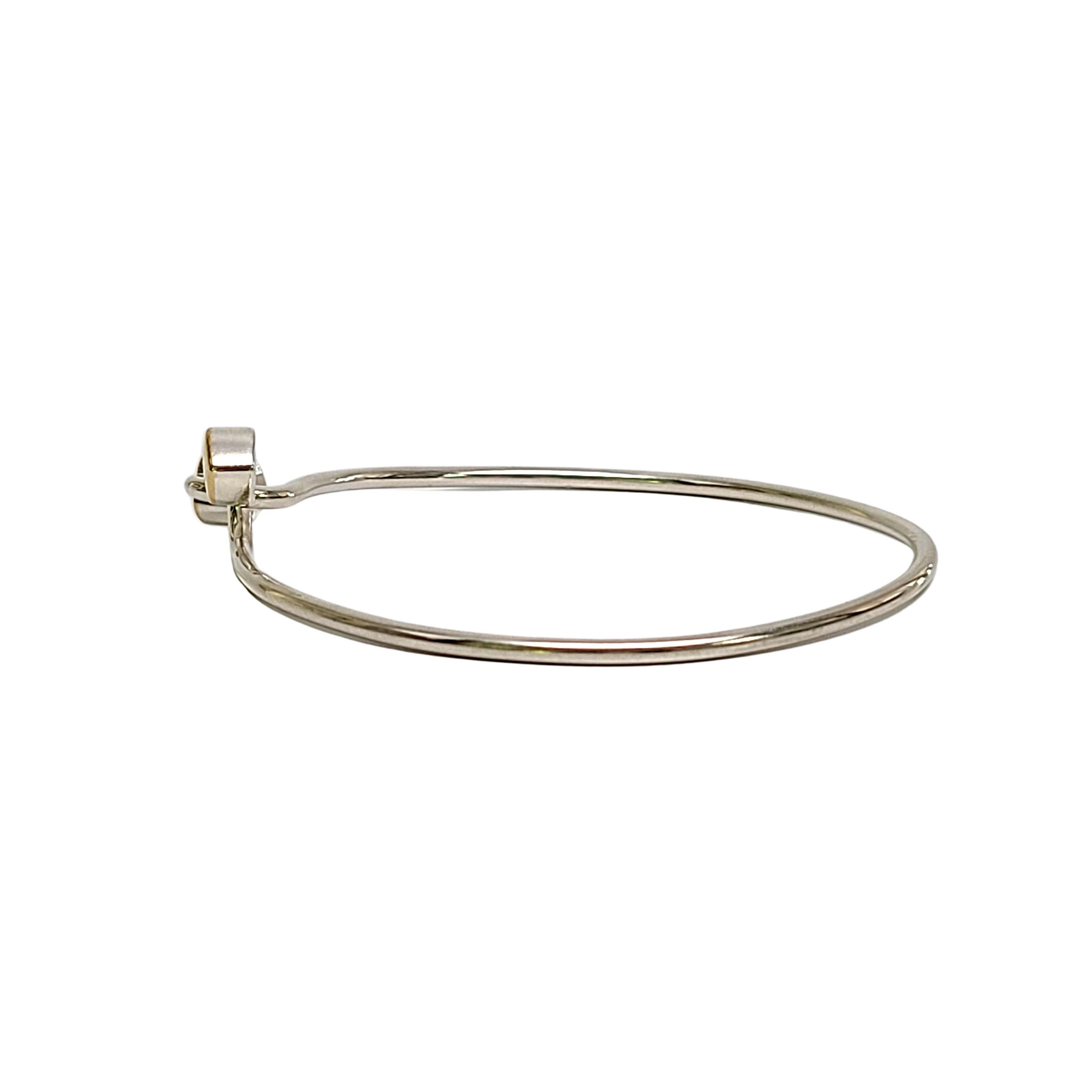 Tiffany & Co sterling silver and 18K yellow gold double heart hook bangle bracelet.

Authentic Tiffany sterling silver bracelet featuring 2 18K yellow gold accent hearts in an interlocking closure. Tiffany pouch and box not included.

Measures