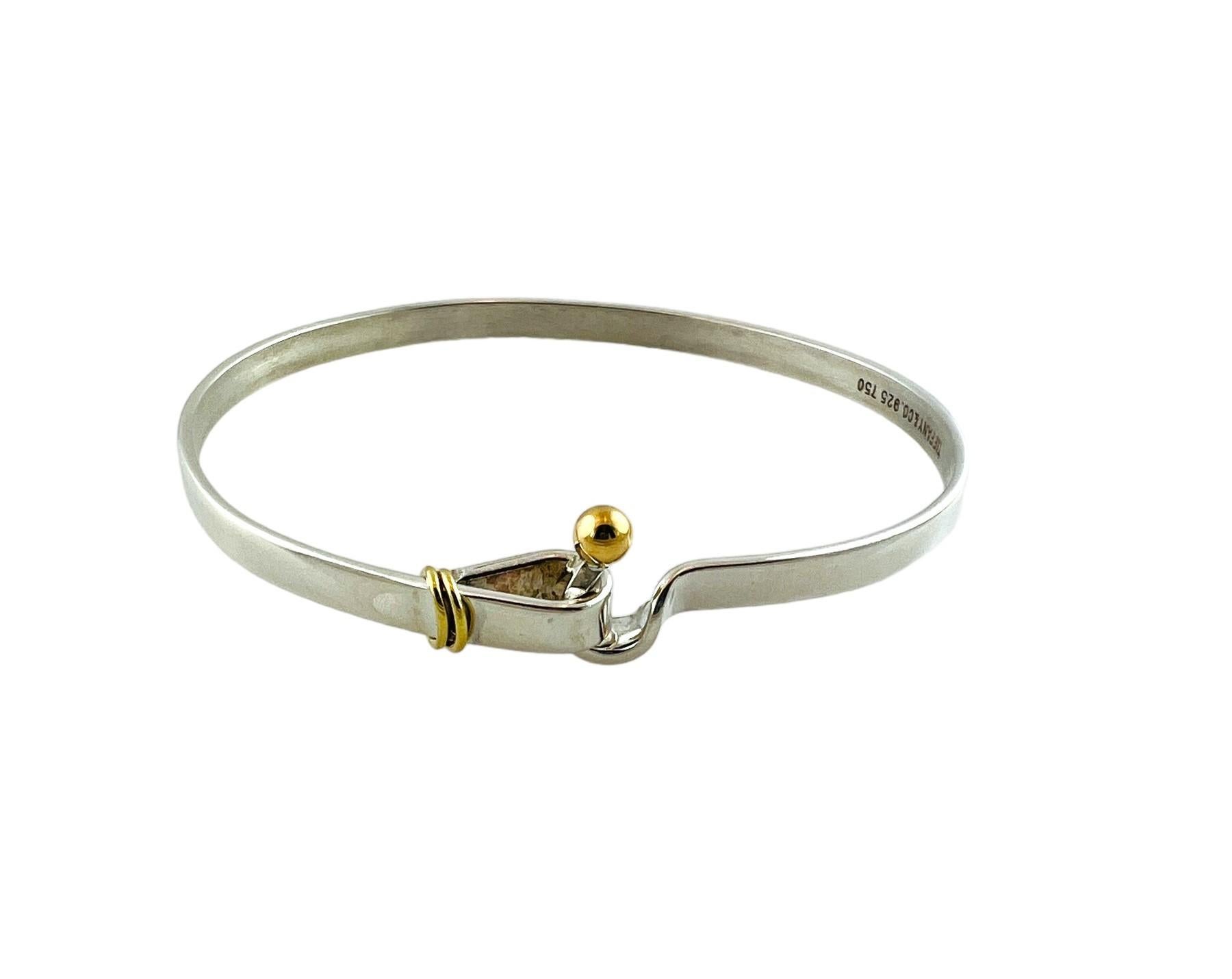 Tiffany & Co sterling silver and 18K bangle bracelet.

Authentic Tiffany sterling silver bracelet, 18K yellow gold accent bead in a hook and eye closure. Tiffany pouch and box not included.

Measures approx 6 3/4