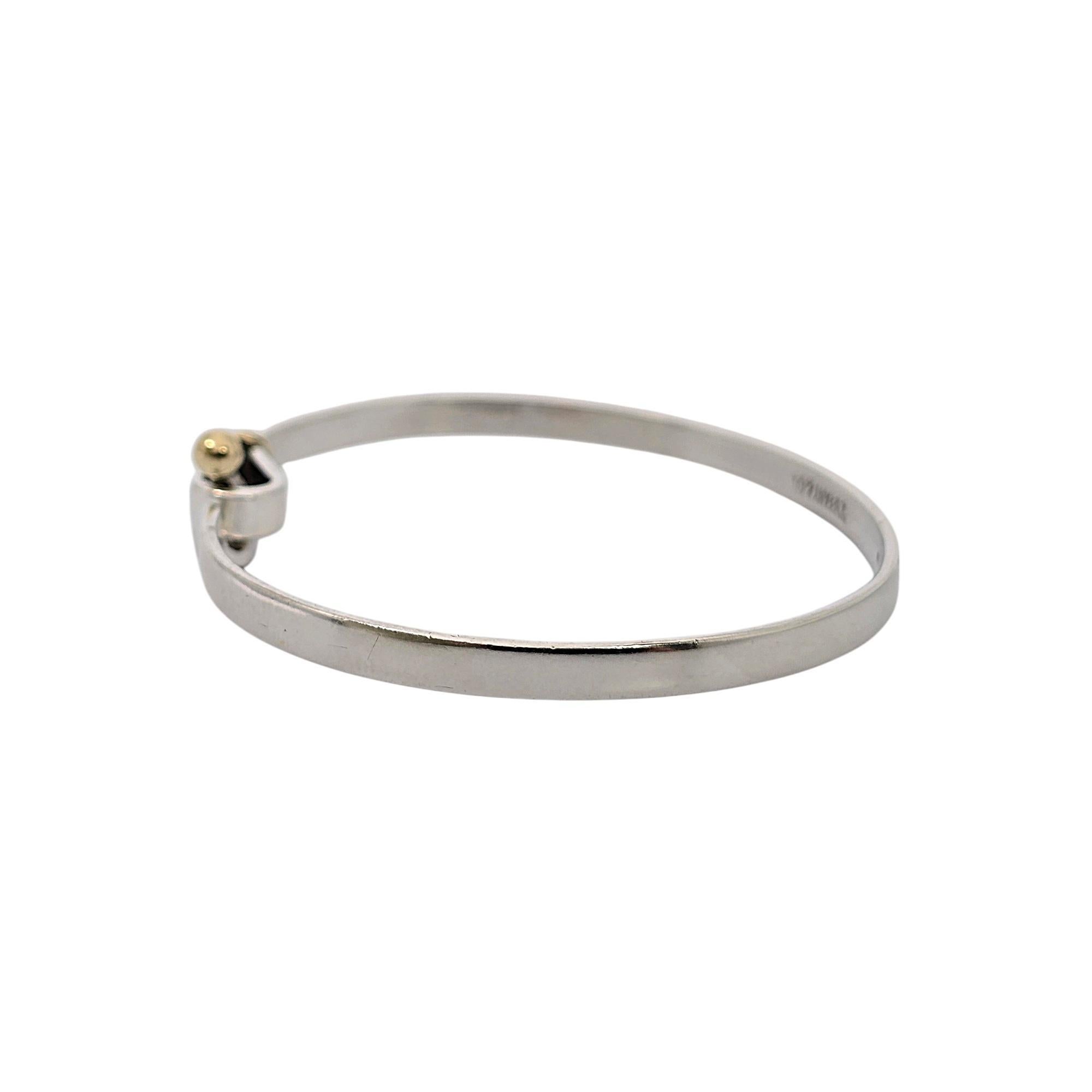 Tiffany & Co sterling silver and 18K yellow gold hook and eye bangle bracelet.

Authentic Tiffany sterling silver bracelet, 18K yellow gold accent bead in a hook and eye closure. Tiffany pouch and box are not included.

Measures approx 6 3/4