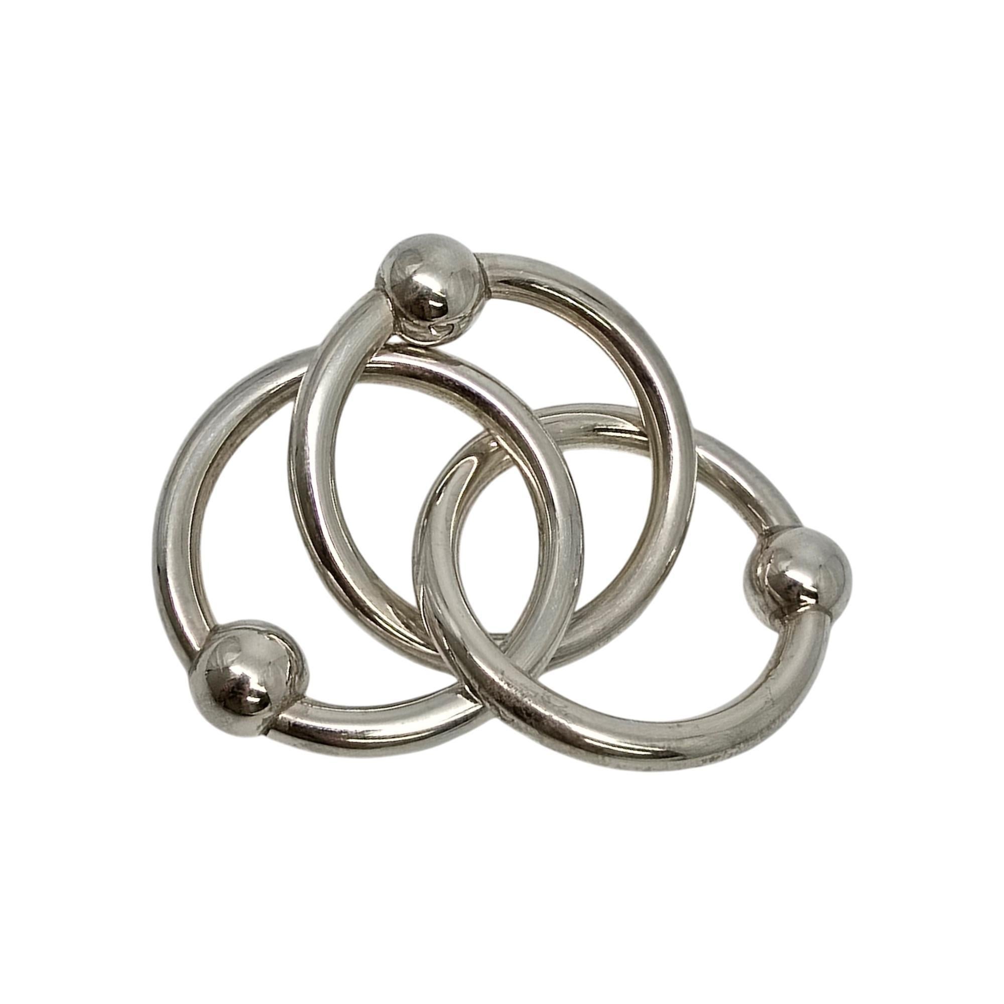 Sterling silver 3 ring baby rattle by Tiffany & Co.

No monogram or engraving.

This is a beautiful and charming authentic sterling silver baby rattle designed by Tiffany & Co featuring 3 interlocking rings, each with a ball detail. It has a soft