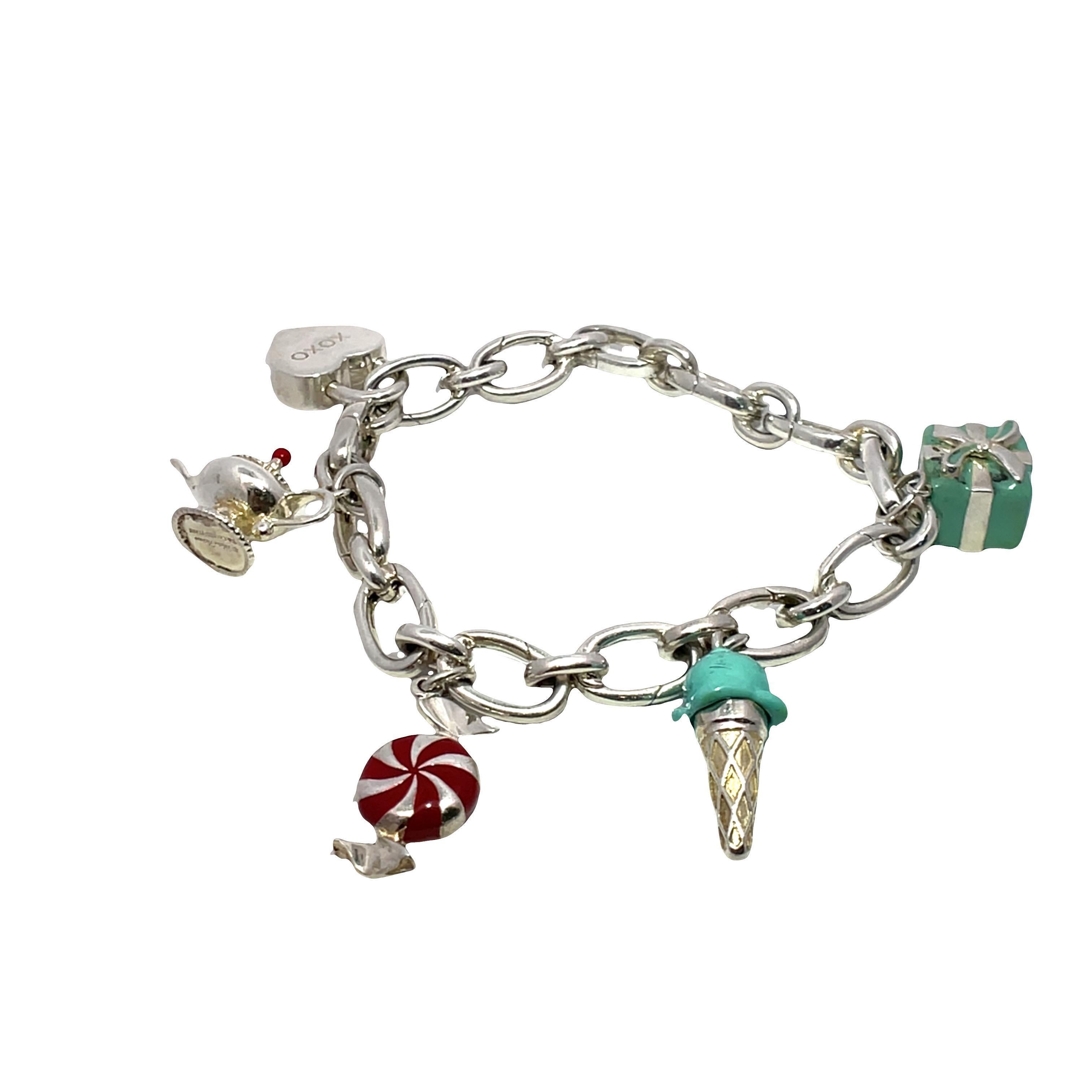 Découvrez le charme ludique de ce bracelet à maillons en argent sterling, un charmant accessoire de Tiffany & Co. Fabriqué avec précision, ce bracelet présente une série de charmes fantaisistes en émail, notamment une lampe Genie de Paloma Picasso,